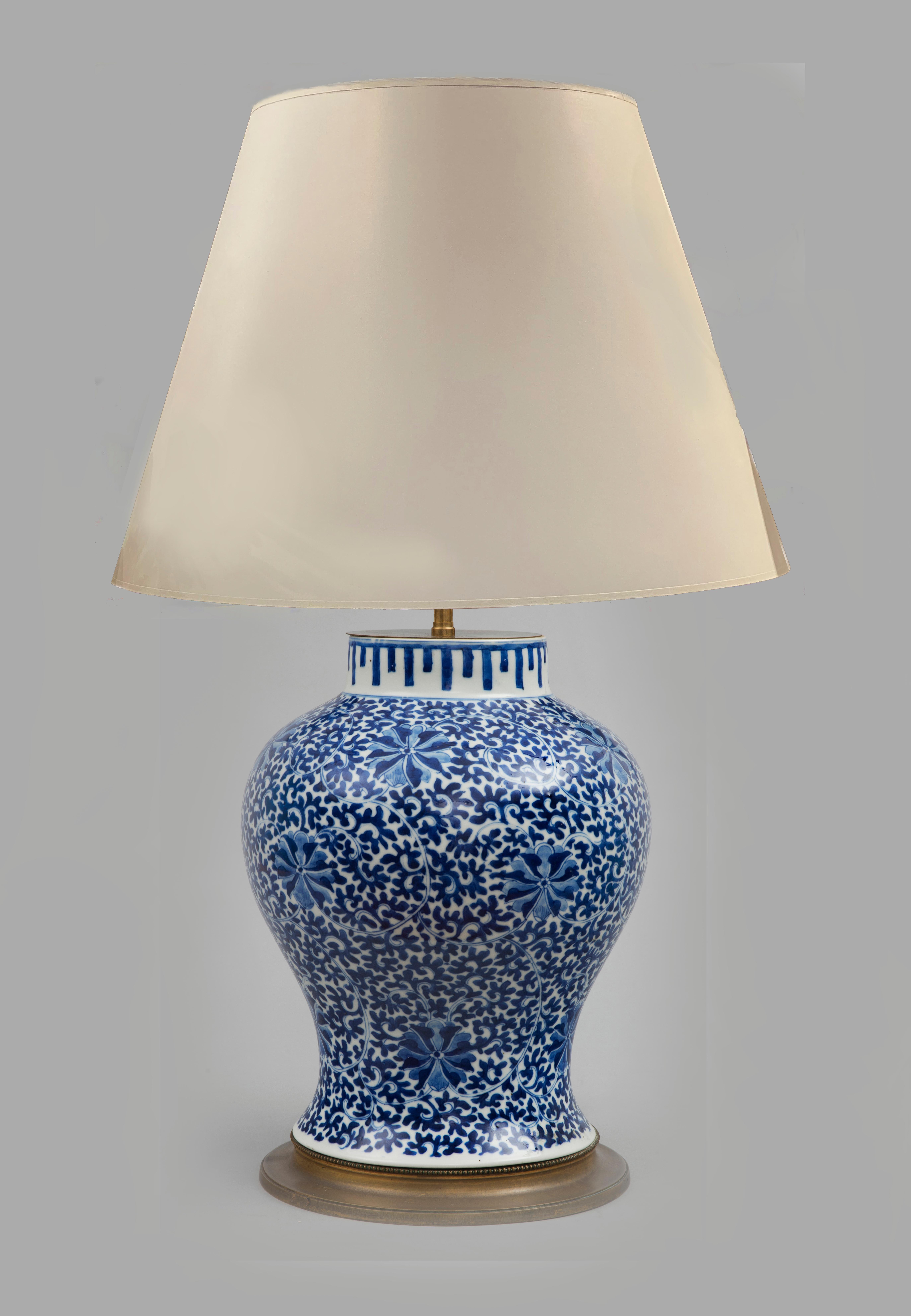 Chinese porcelain blue and white baluster-shaped vase mounted as a lamp, decorated all over with scrolling leaf patterns and stylized flowers, a geometric pattern on the neck, on a brass base, electrified. It has a white paper shade.