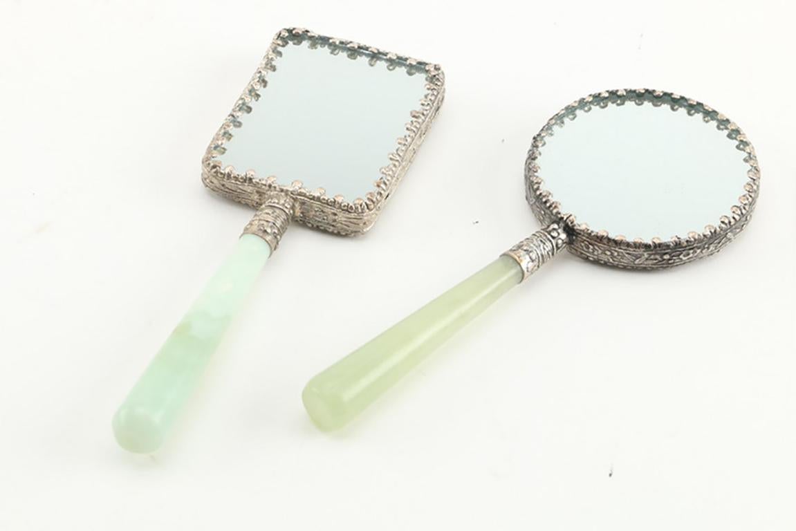 A Chinese bowenite handled magnifying glass and two hand held mirrors with hand painted porcelain insets. All three items have bowenite handles and silver tone metal accents.
 