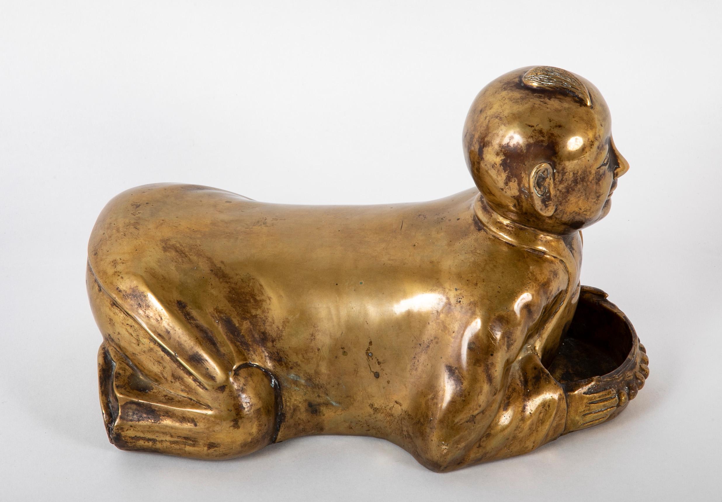Whimsical circa 1900 Chinese brass opium pillow in the form of a kneeling boy. The boy shown crouching and smiling with an amusing forelock on his otherwise bald head. He holds in his hands a tray to rest the opium pipe. Now a wonderful piece of