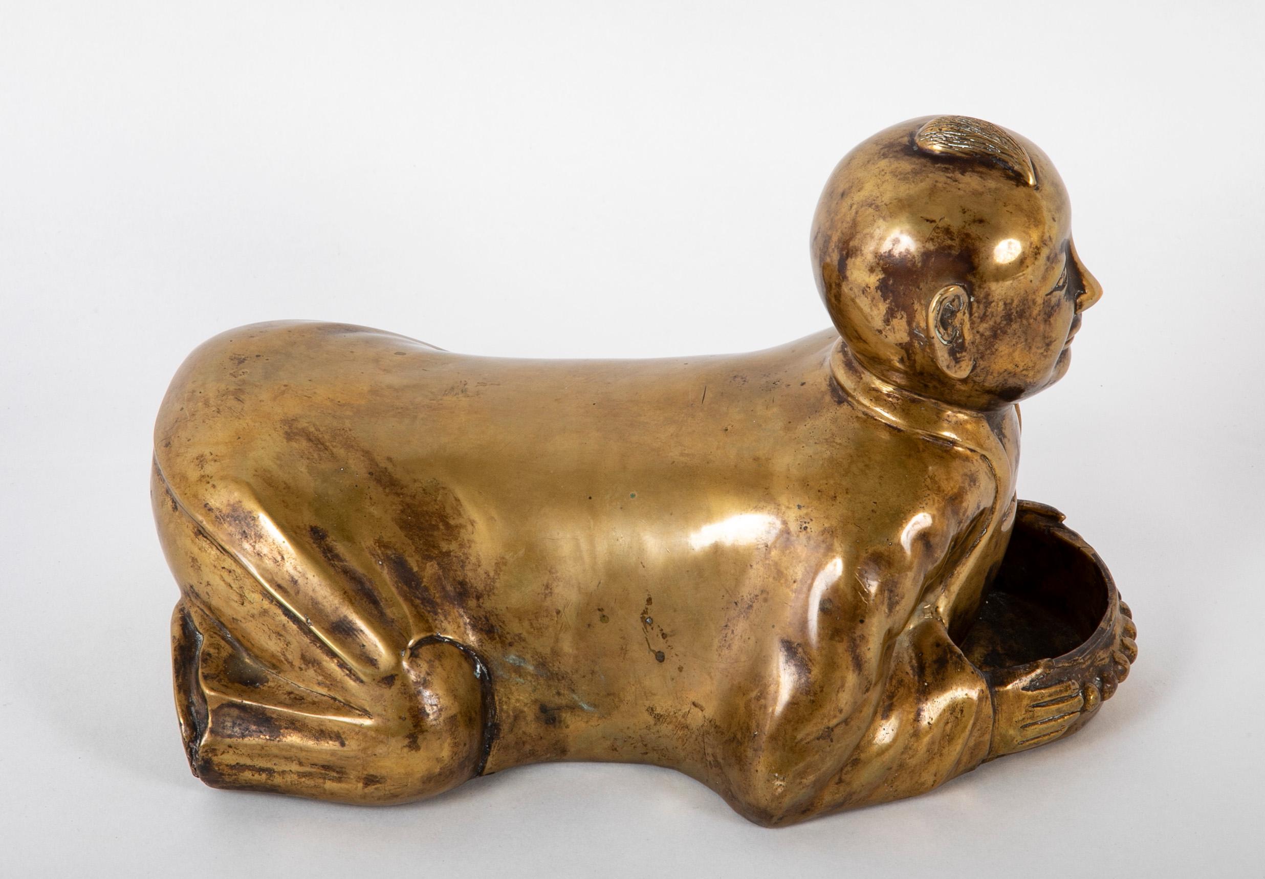 Stravagante cuscino da oppio cinese del 1900 circa in ottone a forma di ragazzo inginocchiato. Il ragazzo è raffigurato accovacciato e sorridente con un divertente ciuffo sulla testa altrimenti calva. An tiene in mano un vassoio per appoggiare la