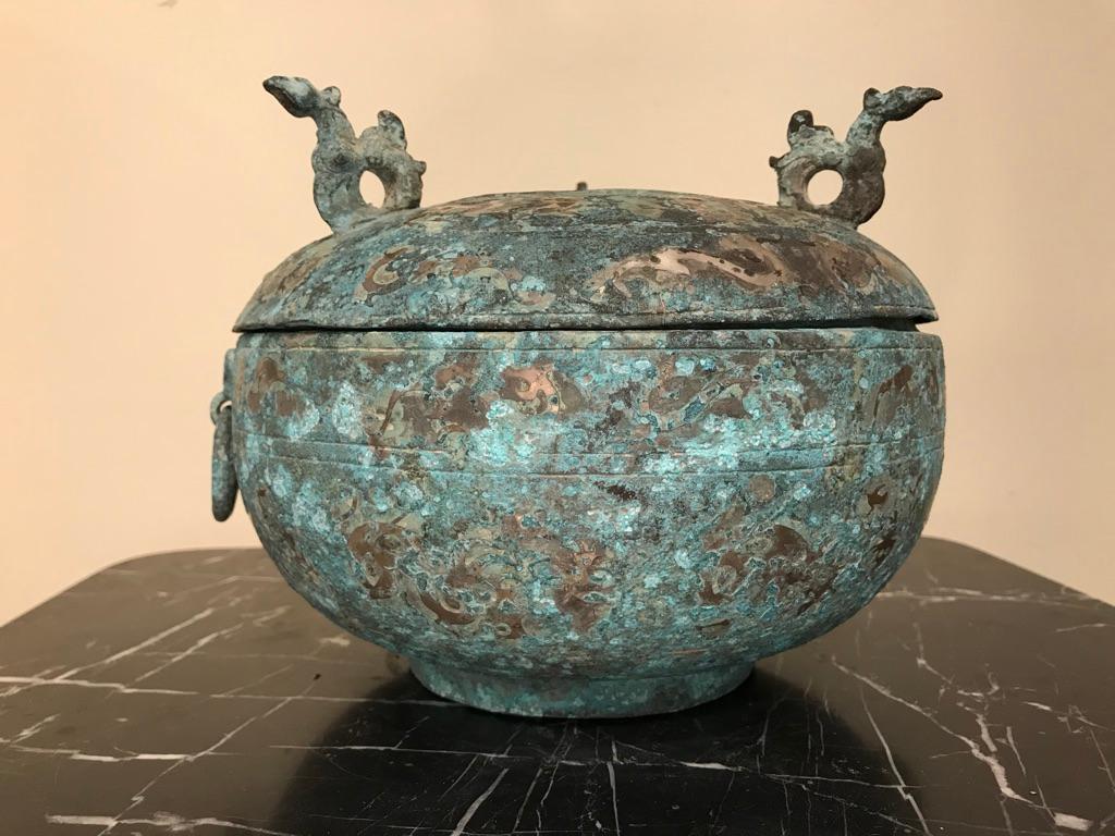 A Chinese silver inlaid bronze lidded ritual vessel modeled after a late Shang dynasty, 1600-1046 BC original. Of Classic form, with bird form handles on the top and ring handles held by Taotie masks on the bowl. The overall surface covered with