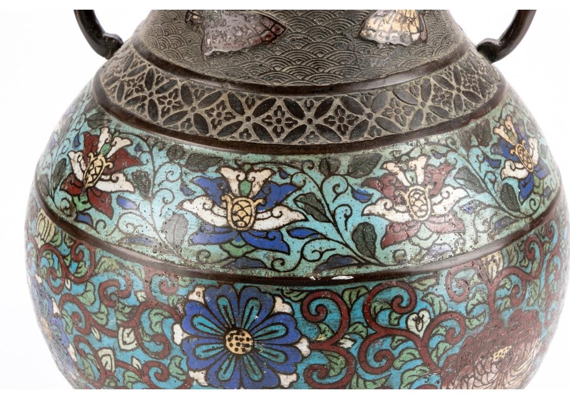 A large vessel with great traditional Archaic form and color. Bronze with twin elephant head handles, enamel butterflies on the neck, and bands of geometric and enameled floral motifs. Zig zag bands on the neck, base and foot. Chop mark on