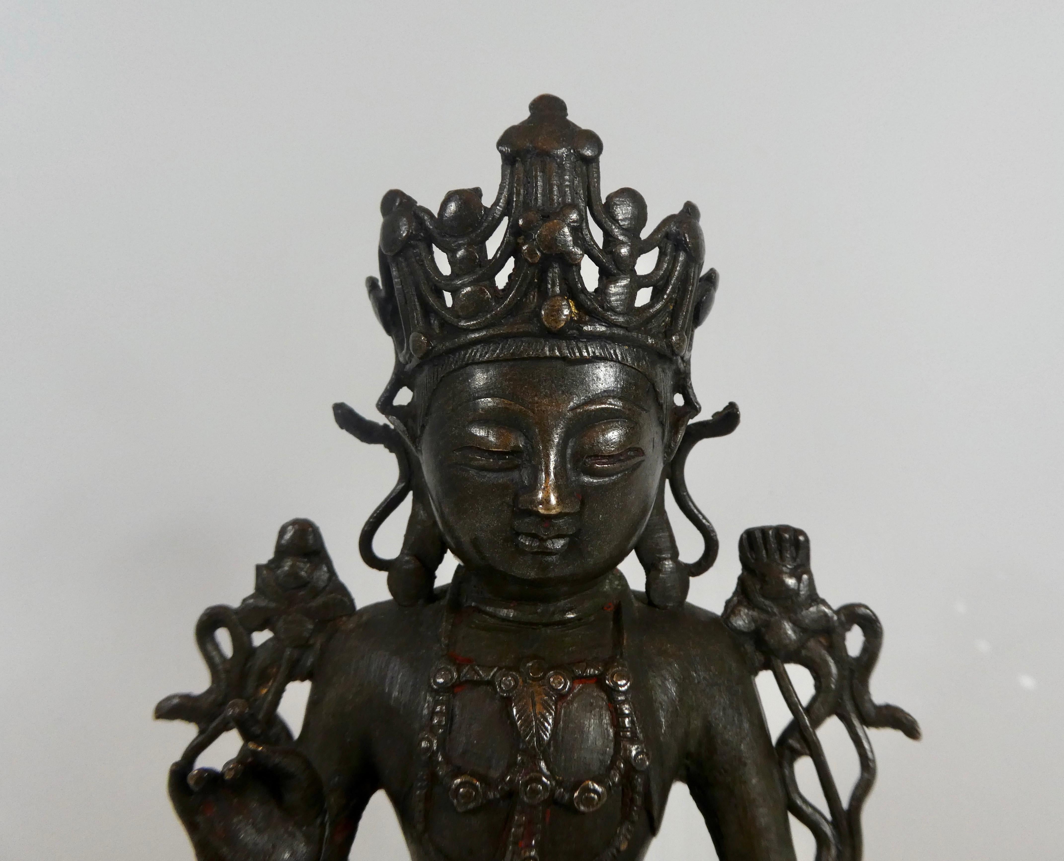 Chinese bronze figure of Guanyin, circa 1600, Ming dynasty. The goddess’ face is cast with a contemplative expression, beneath a five part crown, and she is seated in padmasana with hands in vitarkamudra. Wearing a beaded necklace and girdle, she