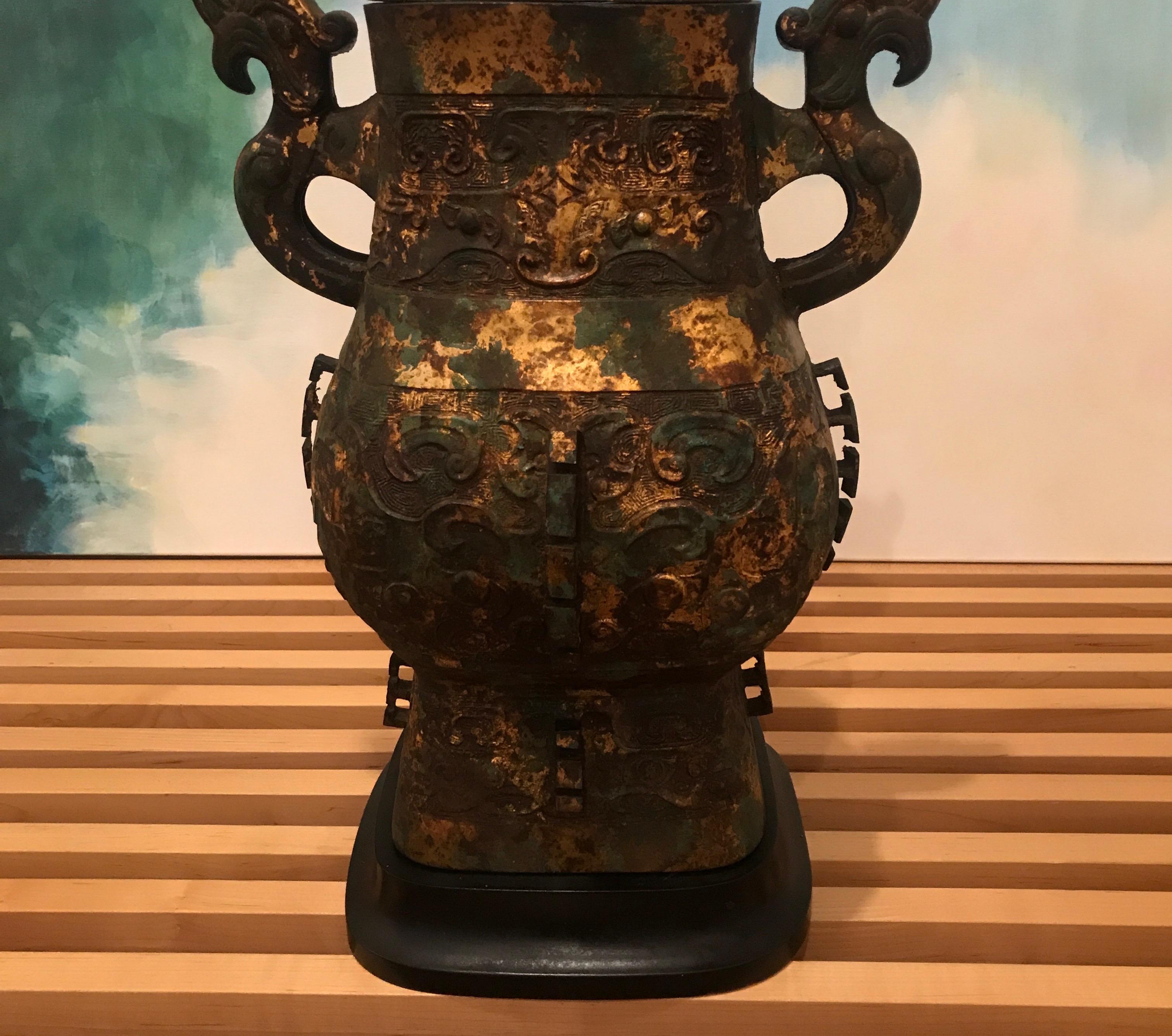 An antique Chinese Archaistic Hu form style bronze urn now as a lamp. The fine heavily detailed surface with an aged gilt and Verdi green finish, the original from an ancient form, this version being from the early 20th century. The vase is 15.5