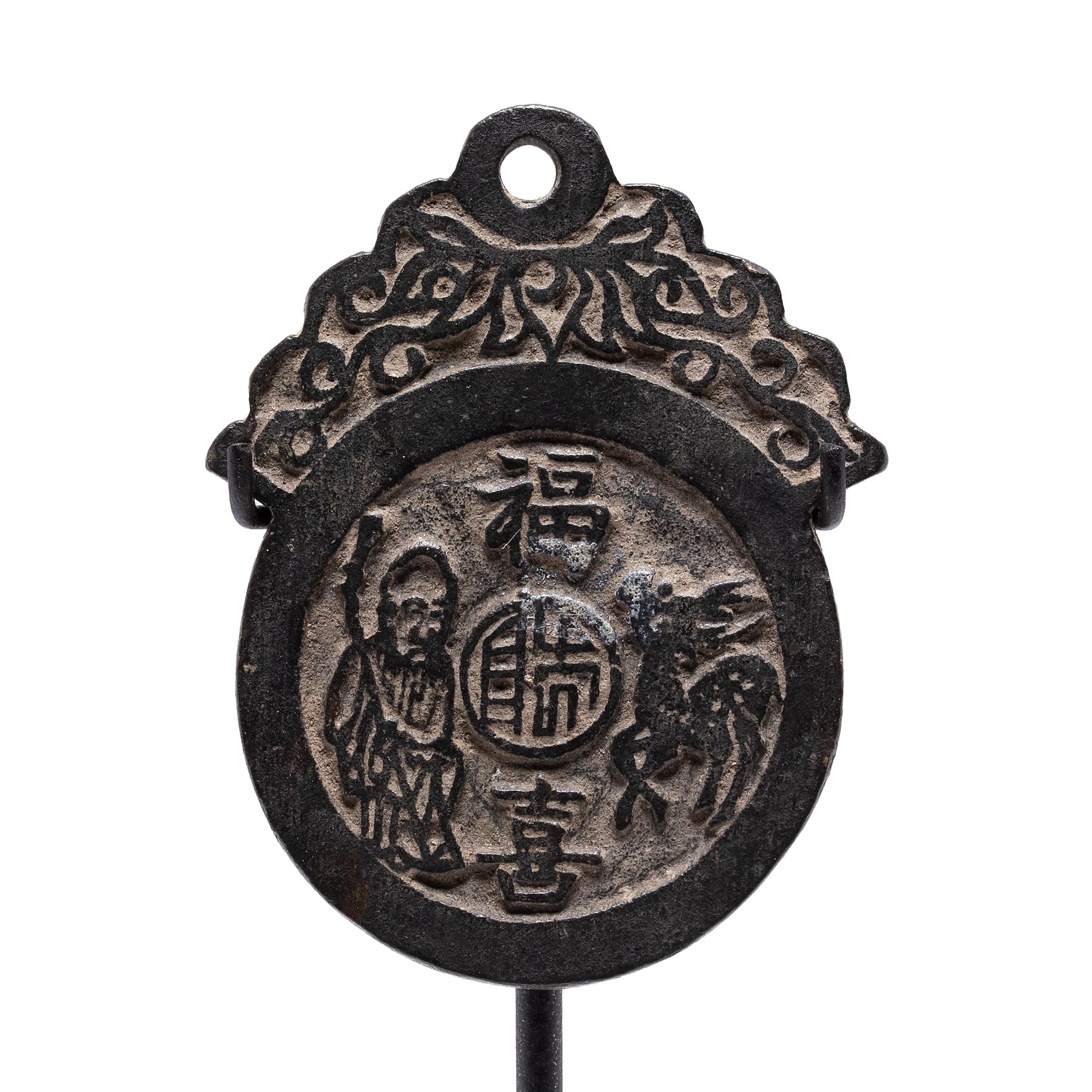 This antique metal amulet was once worn around the neck as a charm for lifelong happiness and professional success. The round amulet is cast of bronze in low relief and decorated with three central characters for happiness, longevity, and good
