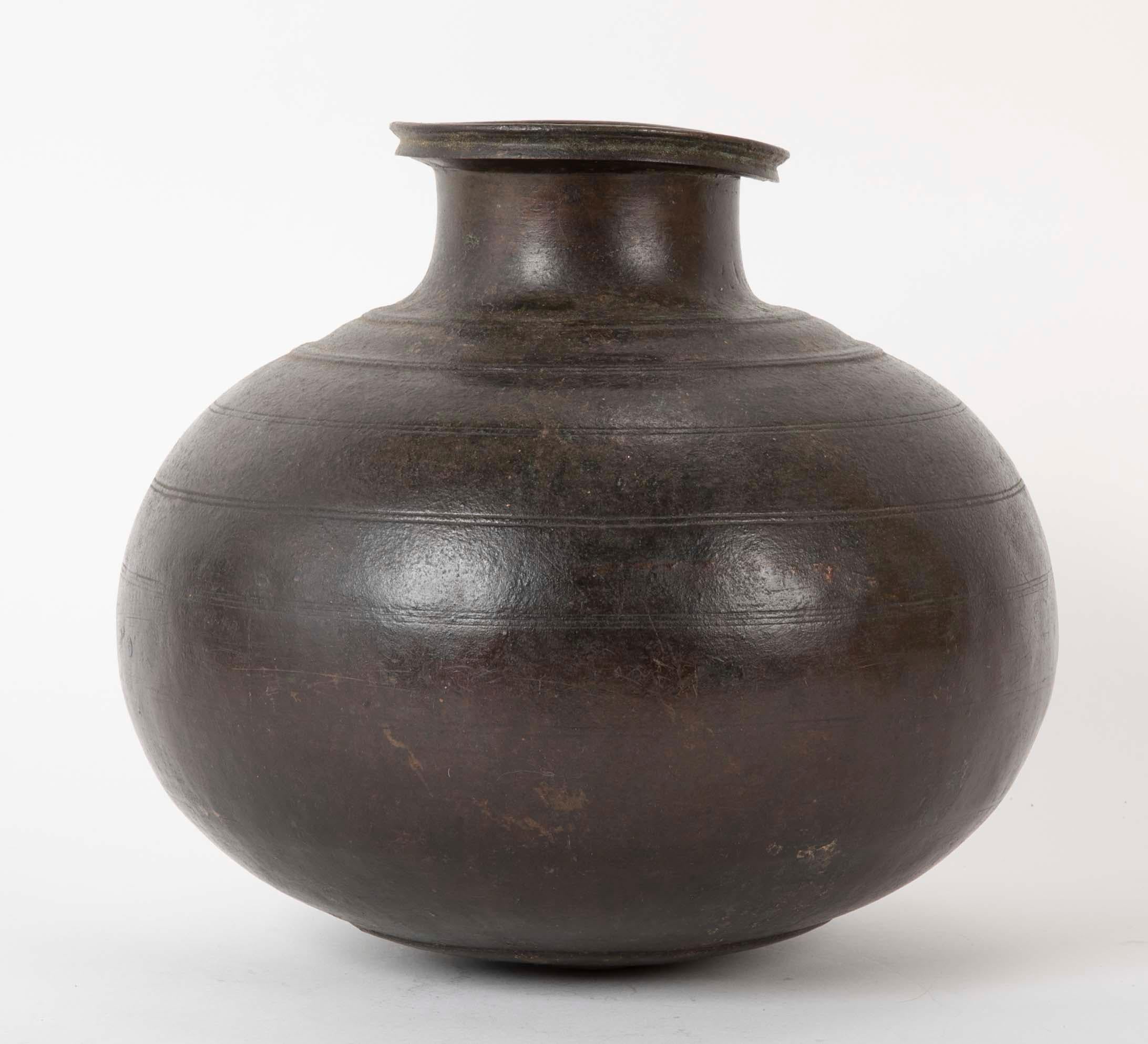 19th century (or earlier) Chinese bronze round wine or oil storage jar. The raised lip of the top dented on one side just adds some character to the piece. The body decorated with incised concentric circles. Deep chocolate patina.