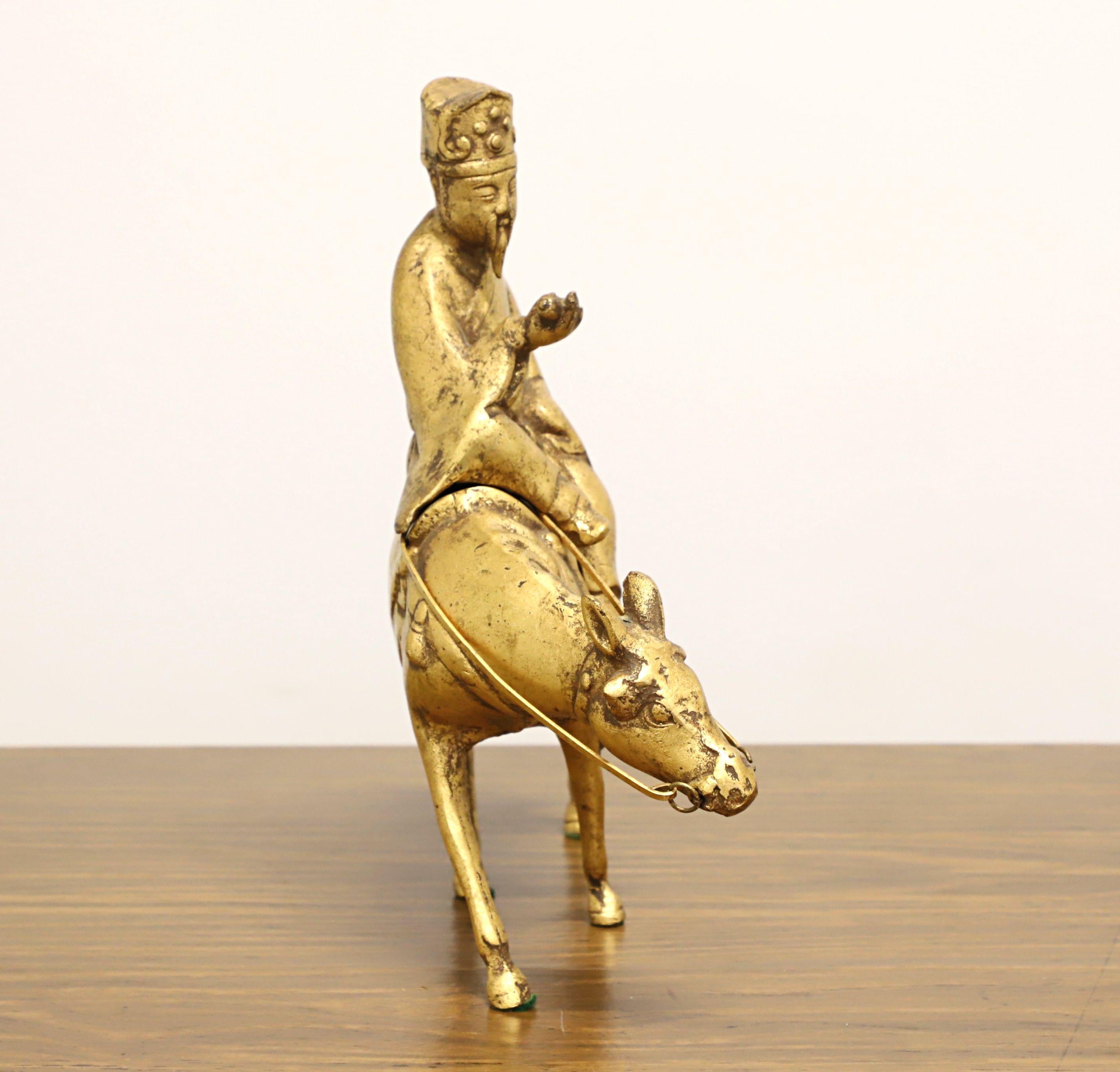 A vintage Chinese table top incense burner sculpted in bronze depicting a scholar riding a horse. Unsigned, artist unknown. Solid bronze of two pieces with a bronze and gold tint. Scholar removes from horse for incense placement. Likely made in