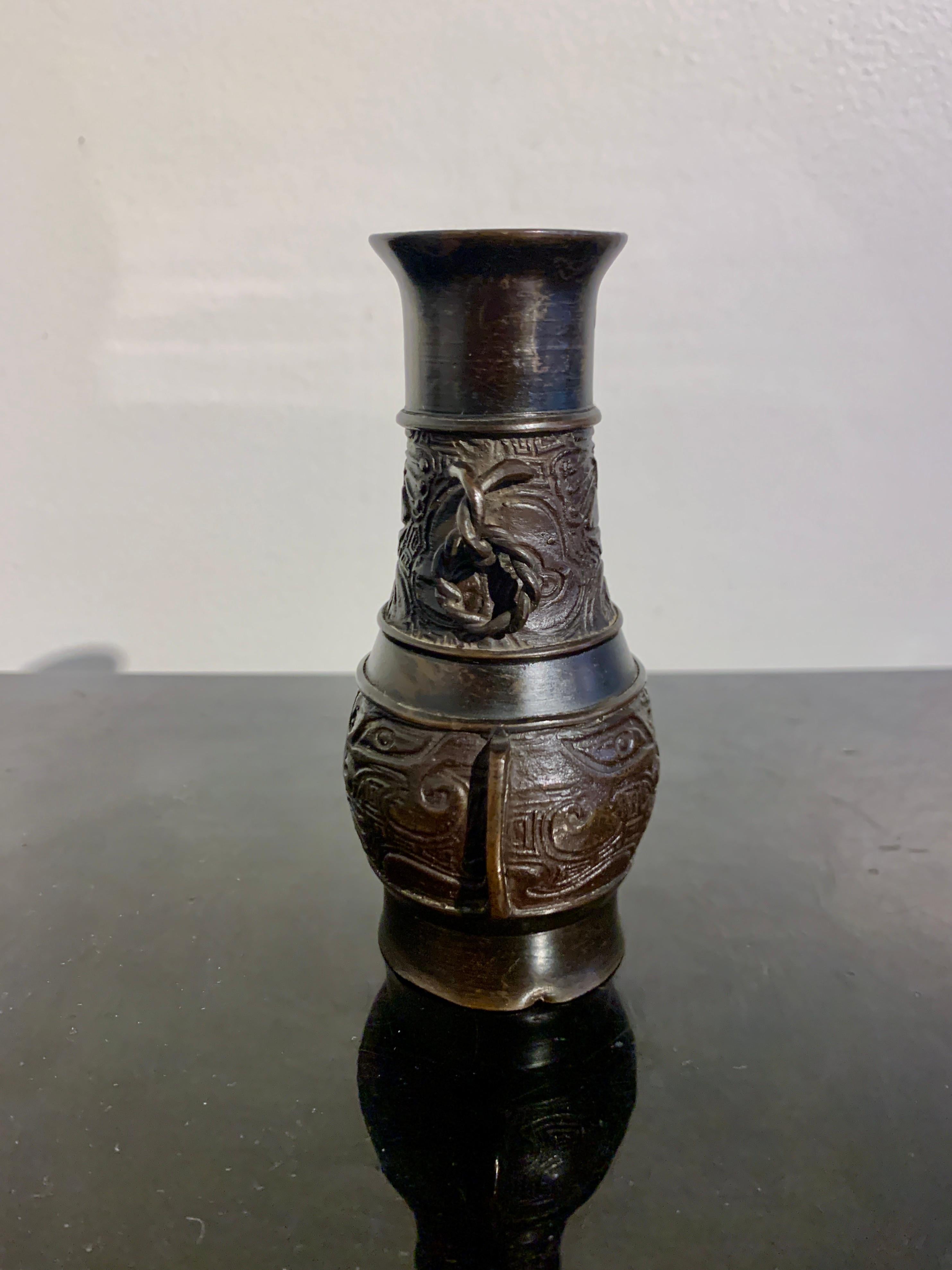 A small and interesting cast bronze archaistic scholar vase with loose ring handles and taotie mask design, late Ming or early Qing Dynasty, mid 17th century, China.

The small vase of archaistic hu form, and cast with archaistic designs. Sitting