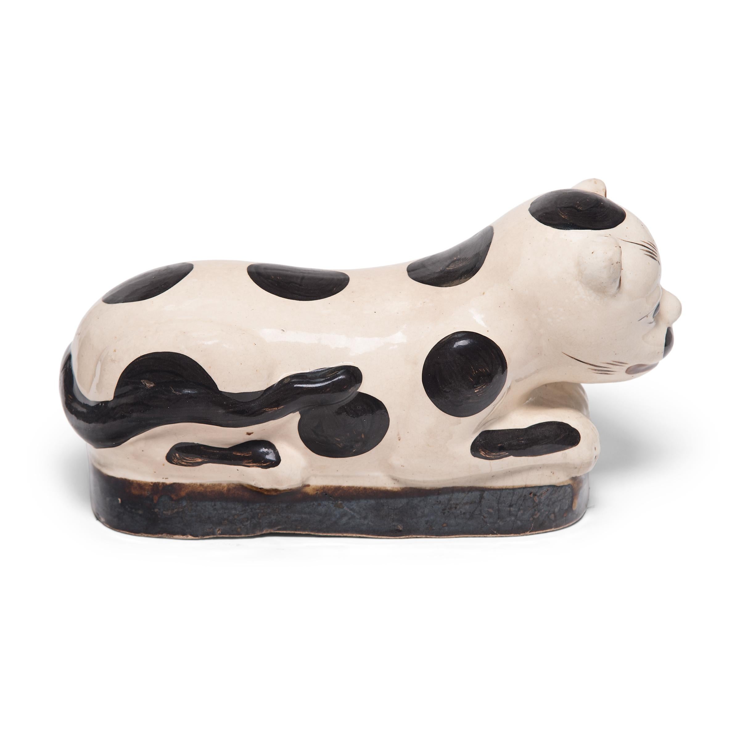 To keep her elaborate hairstyle intact while sleeping, a well-to-do Qing-dynasty woman once used this ceramic headrest as a pillow. The headrest is shaped as a crouching house cat, with whiskers and fur playfully painted in with black, brown, and