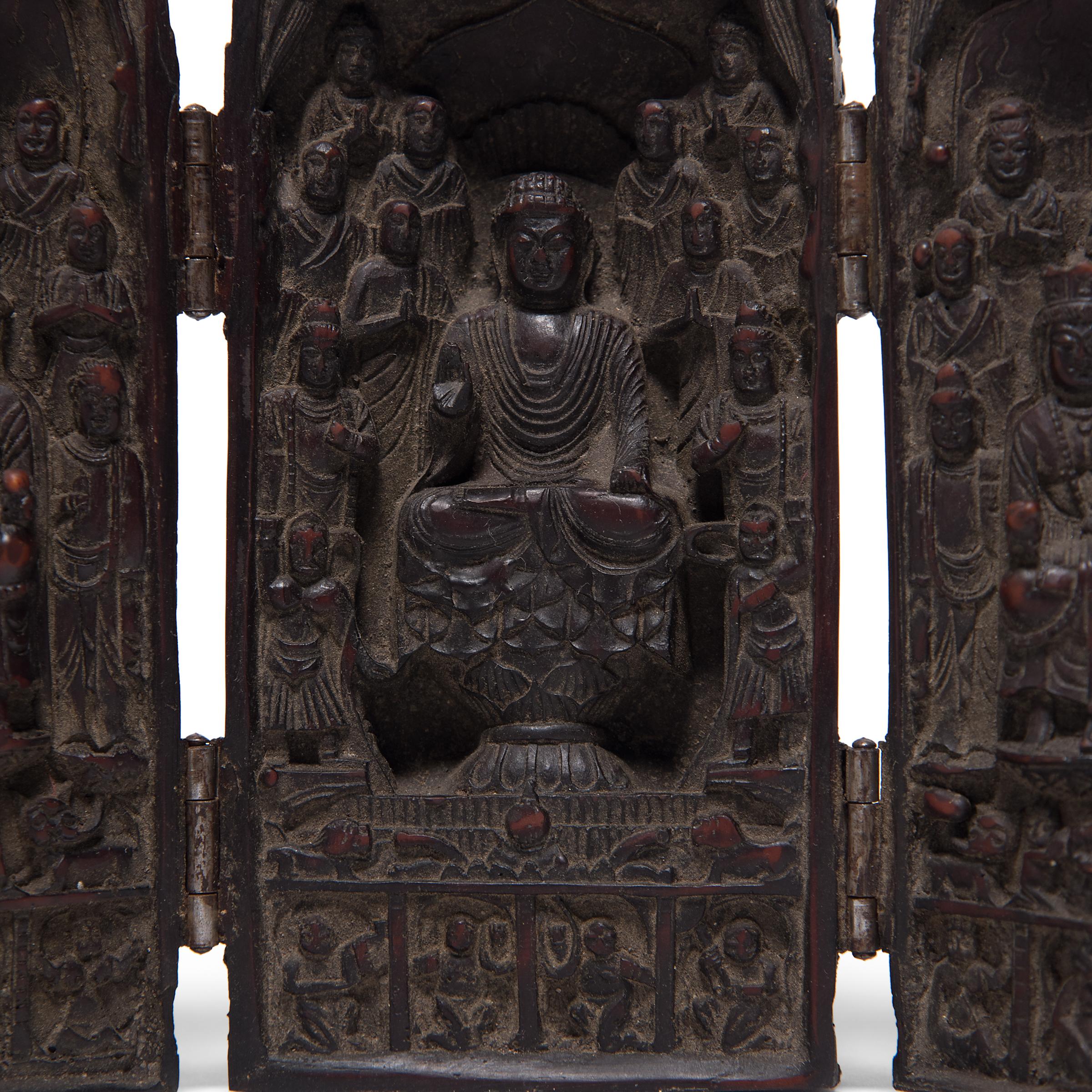 The hinged doors of this petite traveling shrine open to reveal the seated Buddha Shakyamuni surrounded by minor Bodhisattvas and reverent monks. Seated upon a lotus base draped with fabric, the Buddha sits in quiet contemplation with hands in the