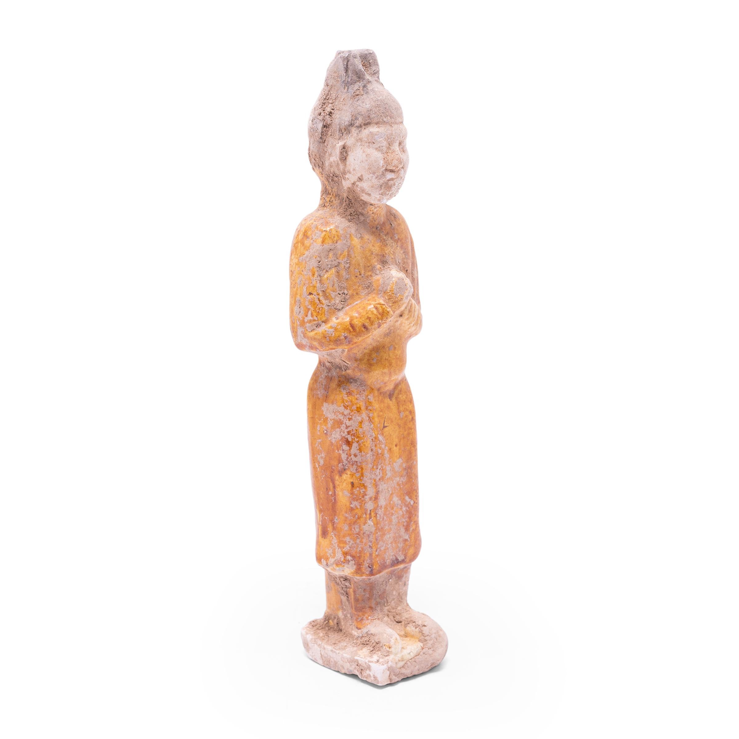 Molded of earthenware, this petite sculpture is a type of centuries-old burial figurine known as míngqì. Such model figures were placed in tombs of individuals with high status to ensure a safe journey to the afterlife. Meant to depict the pleasures