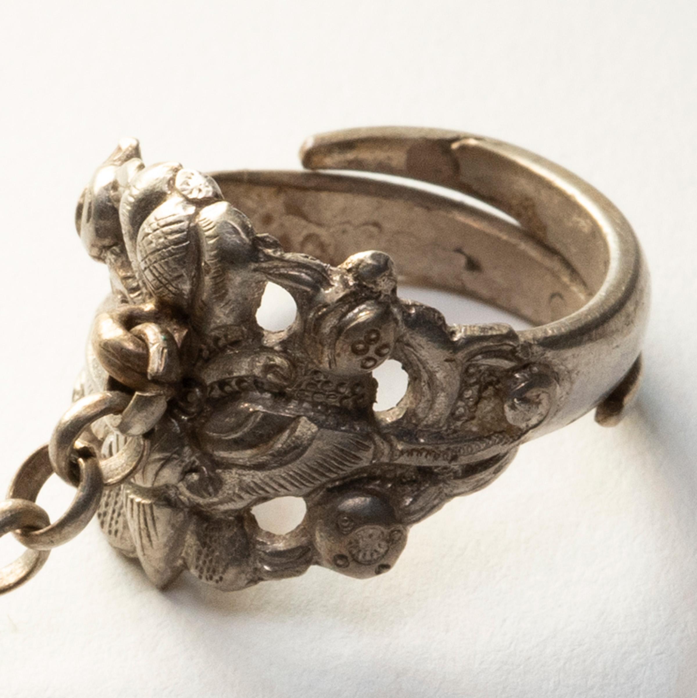 Dated to the late 19th century, this silver charm ring was believed to protect the wearer from bad luck and malevolent spirits. The ring is decorated in relief with a round gourd and a butterfly, surrounded by leaves and small flowers. This motif of