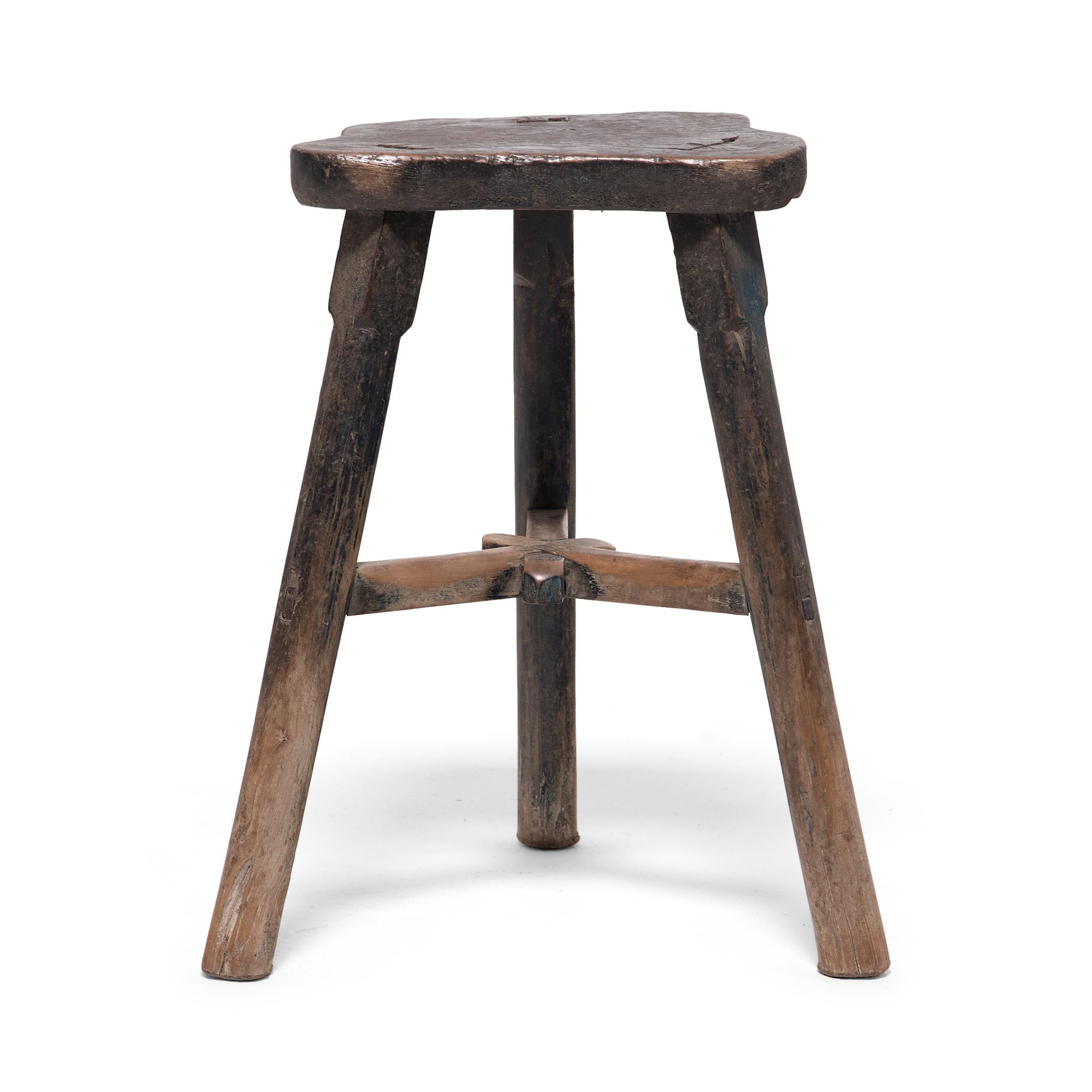 Constructed using mortise-and-tenon joinery, this early 20th century everyday stool from China's Hebei province has a relaxed presence and balanced form. Three round legs support a flat seat that has been cut to the Silhouette of a butterfly, a