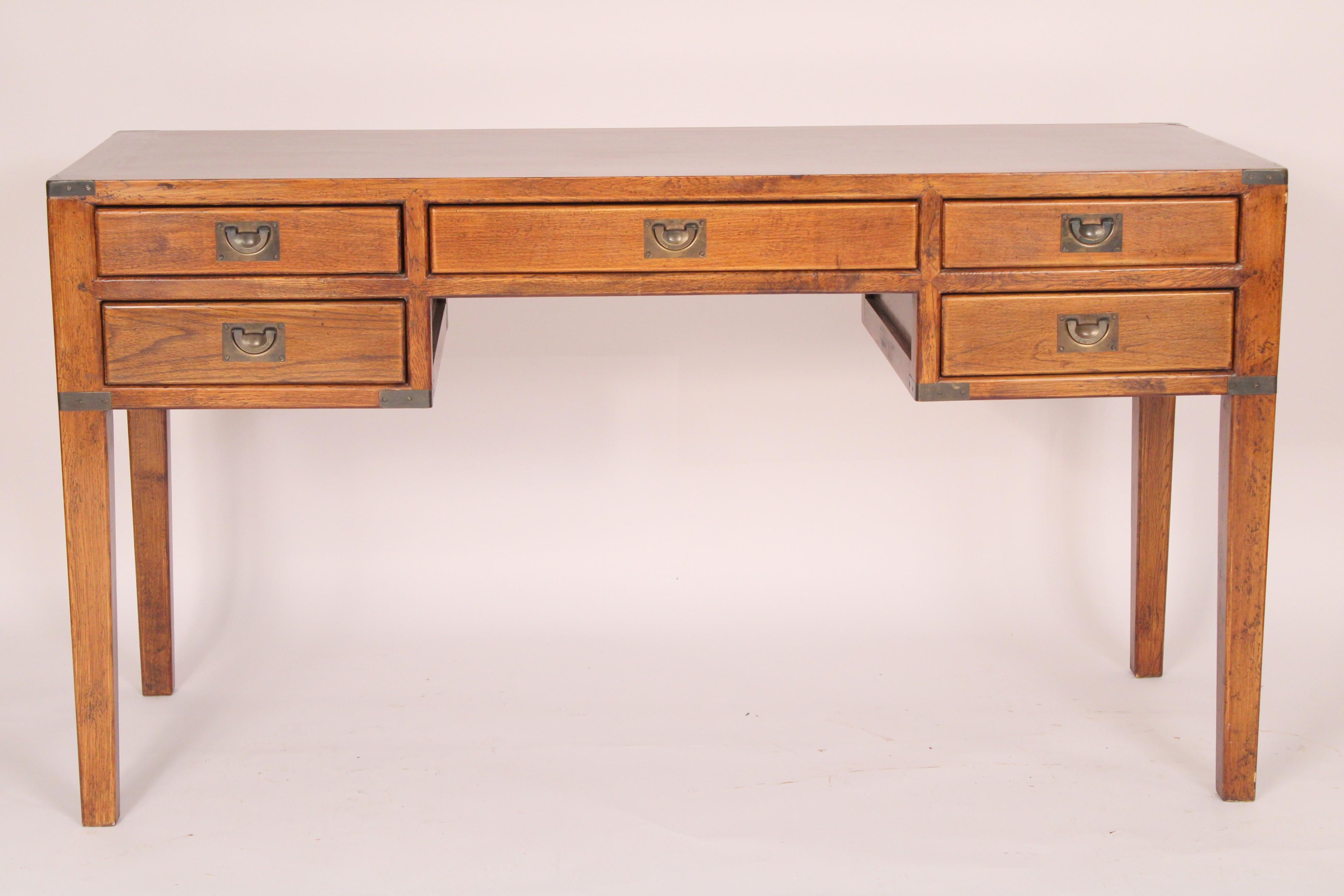 Chinese campaign style elm wood desk, circa 1960's. With a single board  rectangular top, knee hole with center drawer and 2 drawers on either side, all drawers with brass campaign style hardware,  all corners with brass strap  campaign style