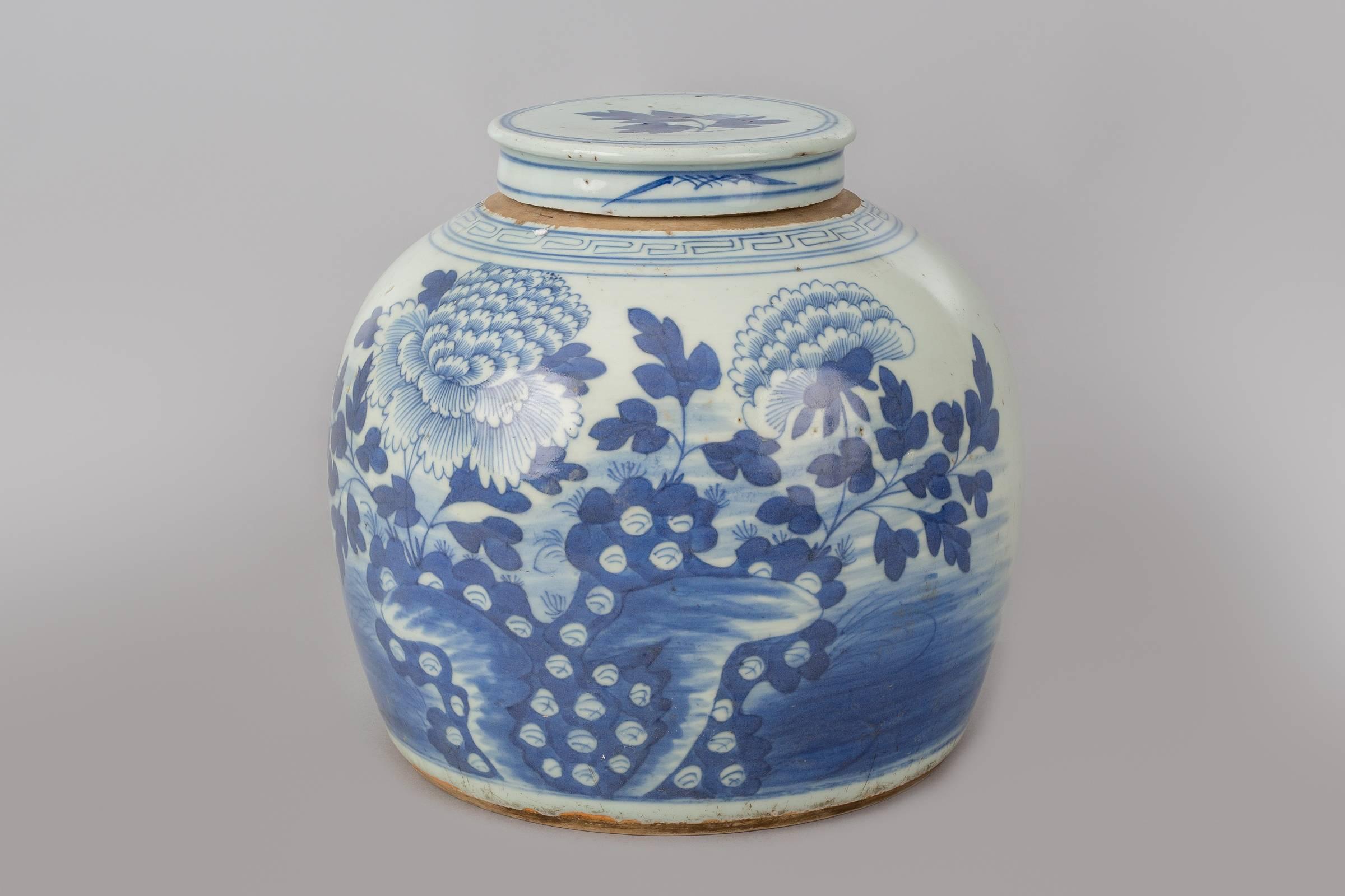 Large Chinese Canton export blue and white porcelain squat vase with lid, decorated with two chrysanthemums and foliage, the shoulder of the vase with geometric key design. The vase sits on a Chinese carved and pierced black wooden stand.