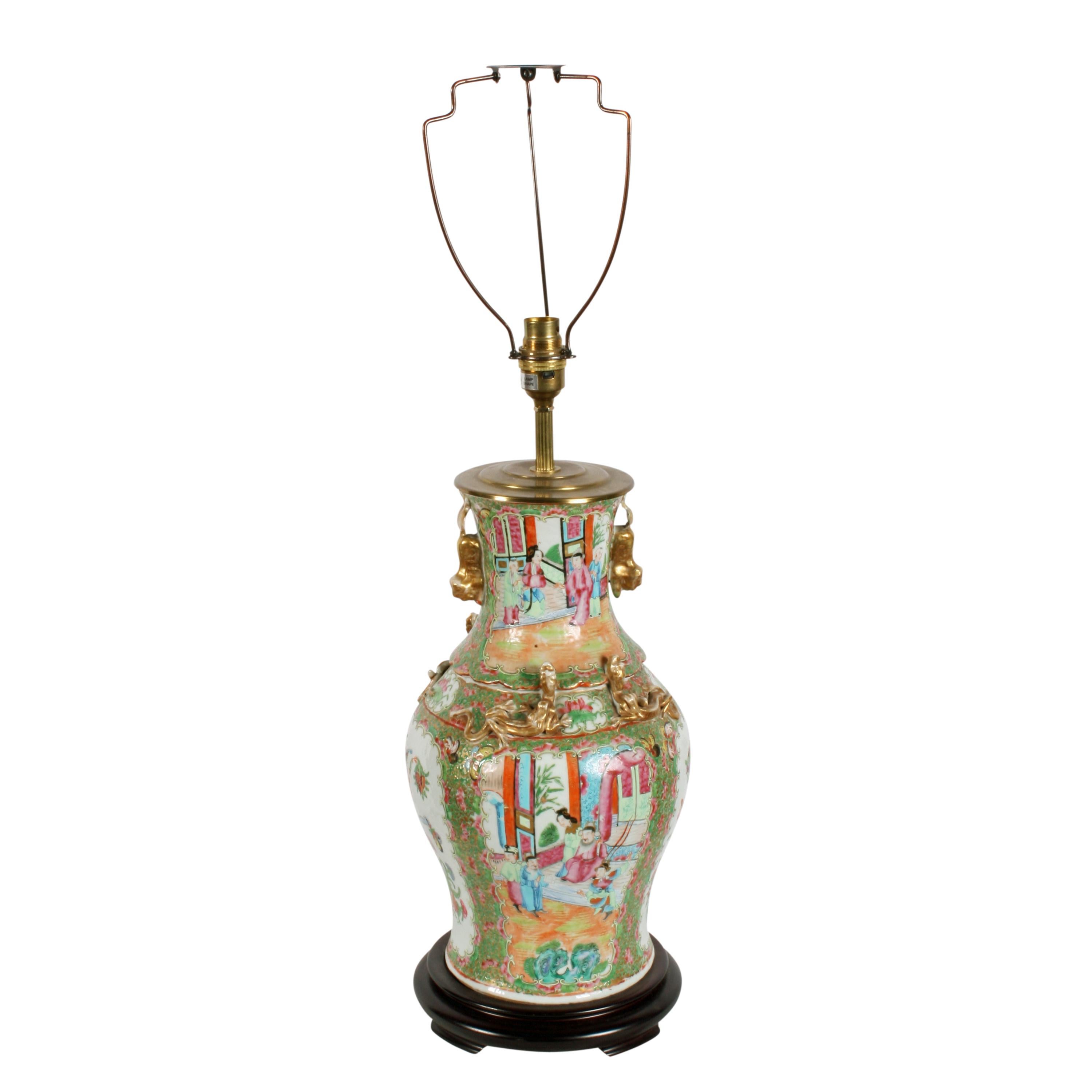 Late 19th century Chinese Canton Porcelain vase converted into a table lamp.


The lamp sits on a fitted turned wood low stand that has four shaped feet.


The porcelain vase is highly decorated with hand painted scenes within panels and