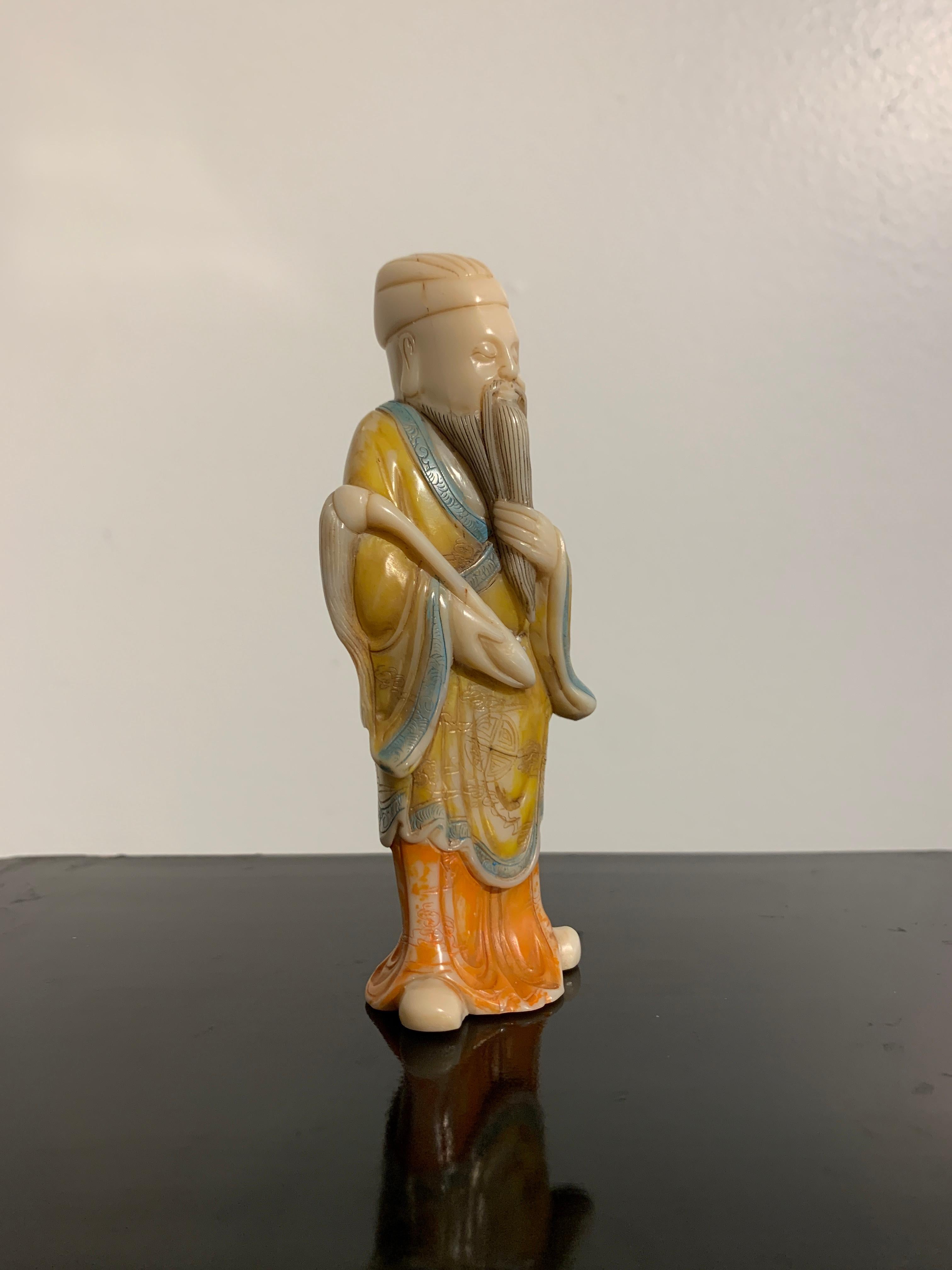 A small, well carved and polychromed Shoushan soapstone figure of a Taoist sage, 20th century, China.

The noble figure is dressed in long court robes painted yellow and orange and decorated with 