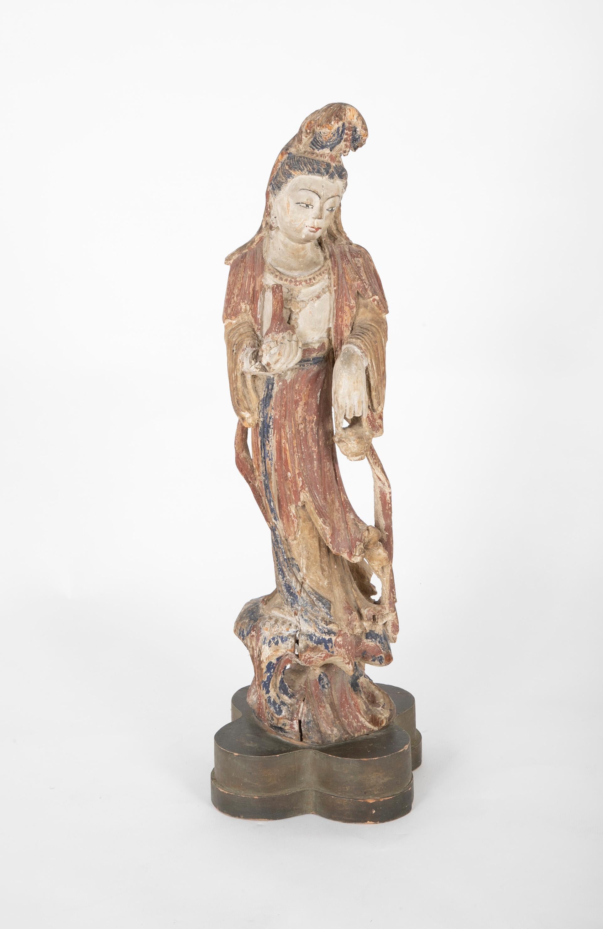 Beautiful carving of Guanyin, shown standing on a rocky outcrop, mounted on a lobed wooden base. It was once used as a lamp, and can be rewired. Nice faded painted surface. 

Guanyin is the Buddhist bodhisattva associated with compassion. She was