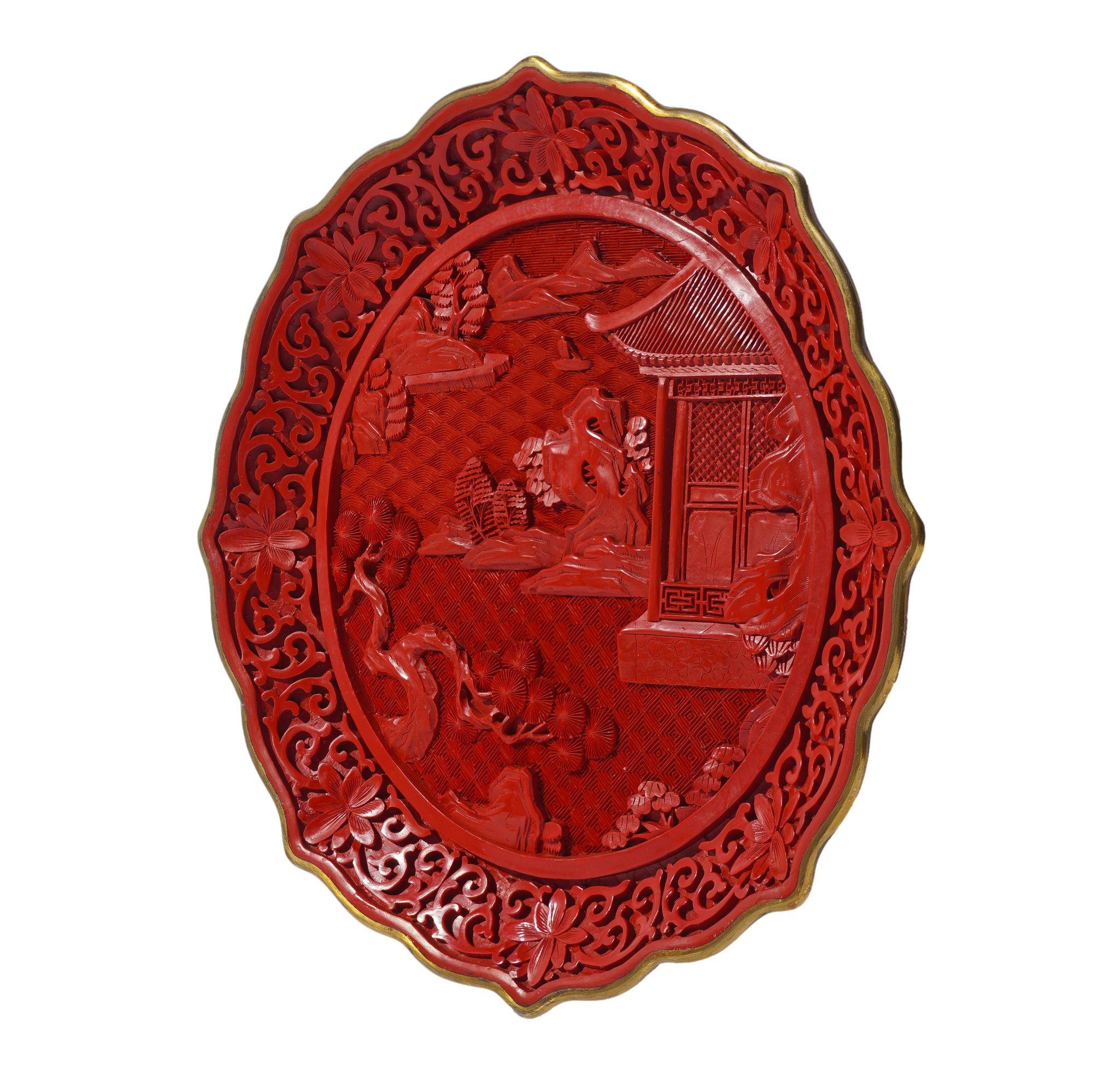 Plaque de cabinet d'exportation en cinabre sculpté de la période de la République chinoise, avec bord festonné en laiton et pied annulaire en laiton. Le paysage central représente un pavillon au bord d'un lac avec des montagnes en arrière-plan. Le