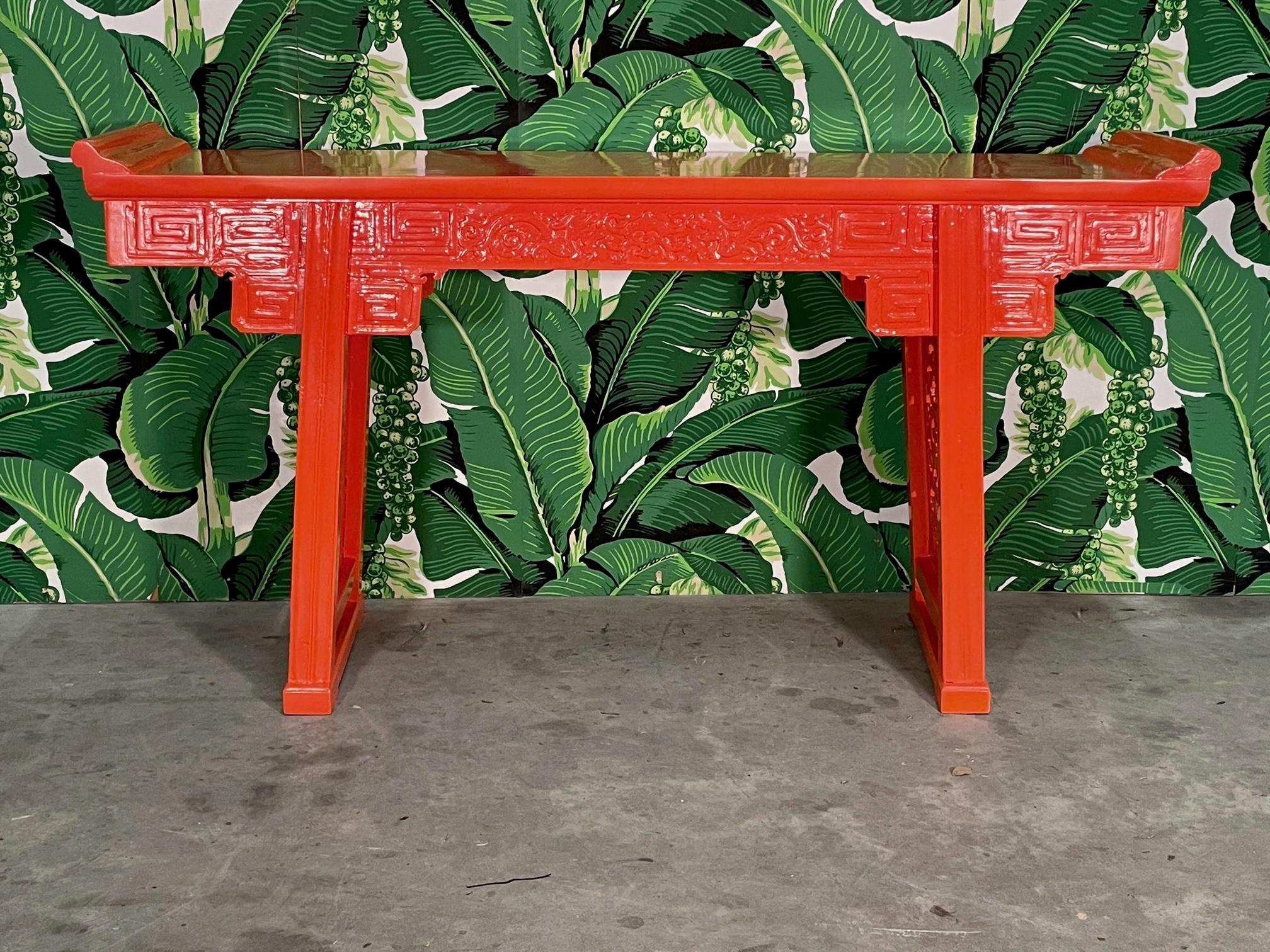 Asian carved altar or console table features hand carved images of dragons along the frieze and ornate snake images in the pierce carved leg struts. Newly high gloss lacquer in an Hermes orange. Stands 36