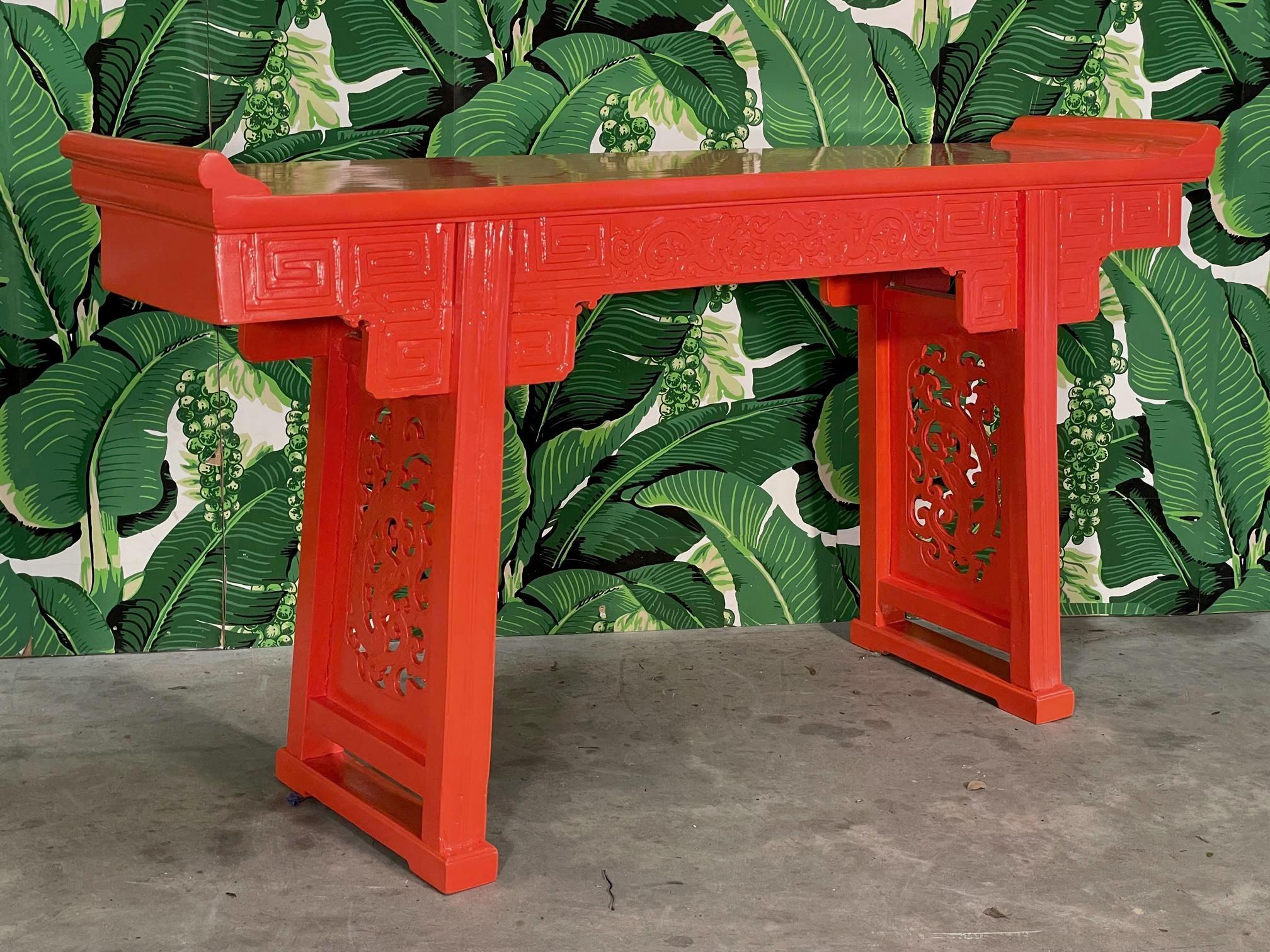 Asian carved altar or console table features hand carved images of dragons along the frieze and ornate snake images in the pierce carved leg struts. Newly high gloss lacquer in an Hermes orange. Stands 36