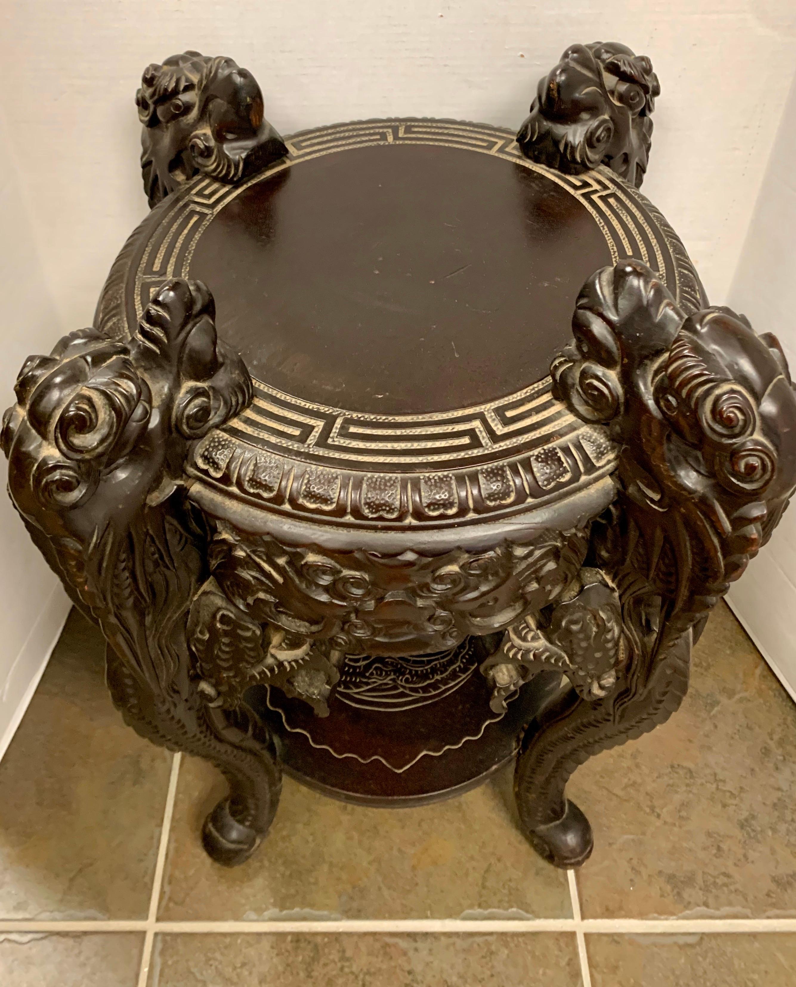 Highly carved round Chinese table supported by four carved dragons. Bottom shelf is engraved with a dragon motif. Top has a carved Greek key border.