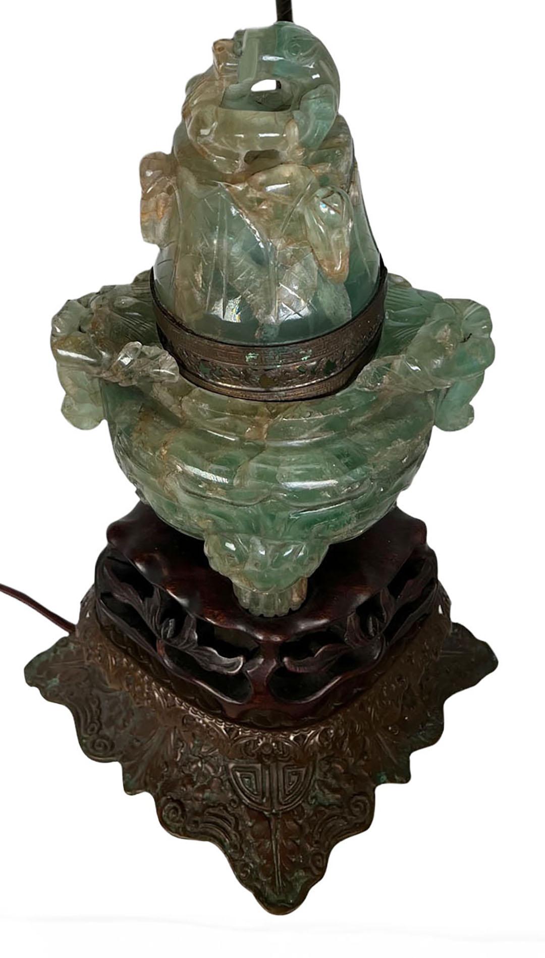 A 1920s Chinese carved green fluorite table lamp. The lid removes to reveal a lightbulb in the interior. The vase and lid are thirteen and a half high.