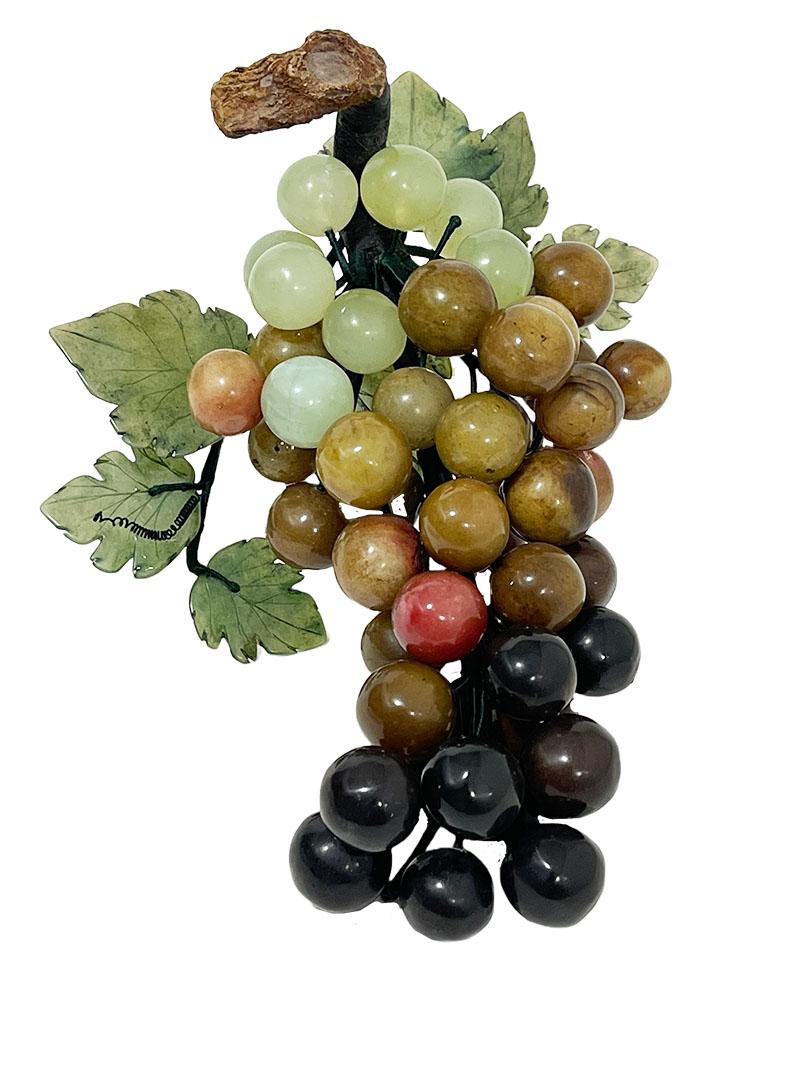 Chinese carved Jade and stone grape cluster, mid-20th century.

Chinese carved beautifully colored stone grapes with silk wrapped wire connection. The end of the bunch has a realistic wooden vine with 7 green jade carved leaves. 2 iron pins with