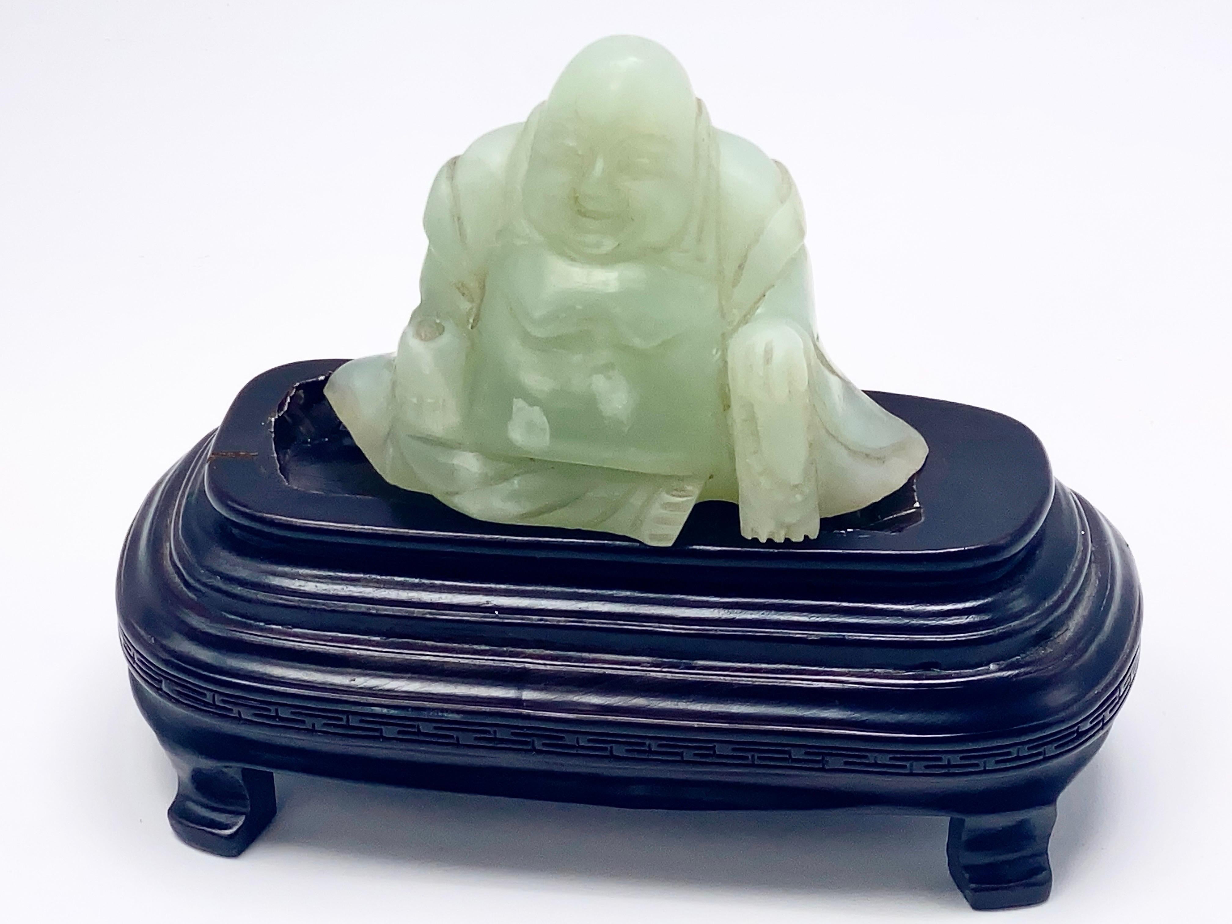 Ce bouddha est en jade, en, une couleur verte. Il est assis sur son socle en bois.
Cela a été fait en Chine au cours du 20ème siècle.