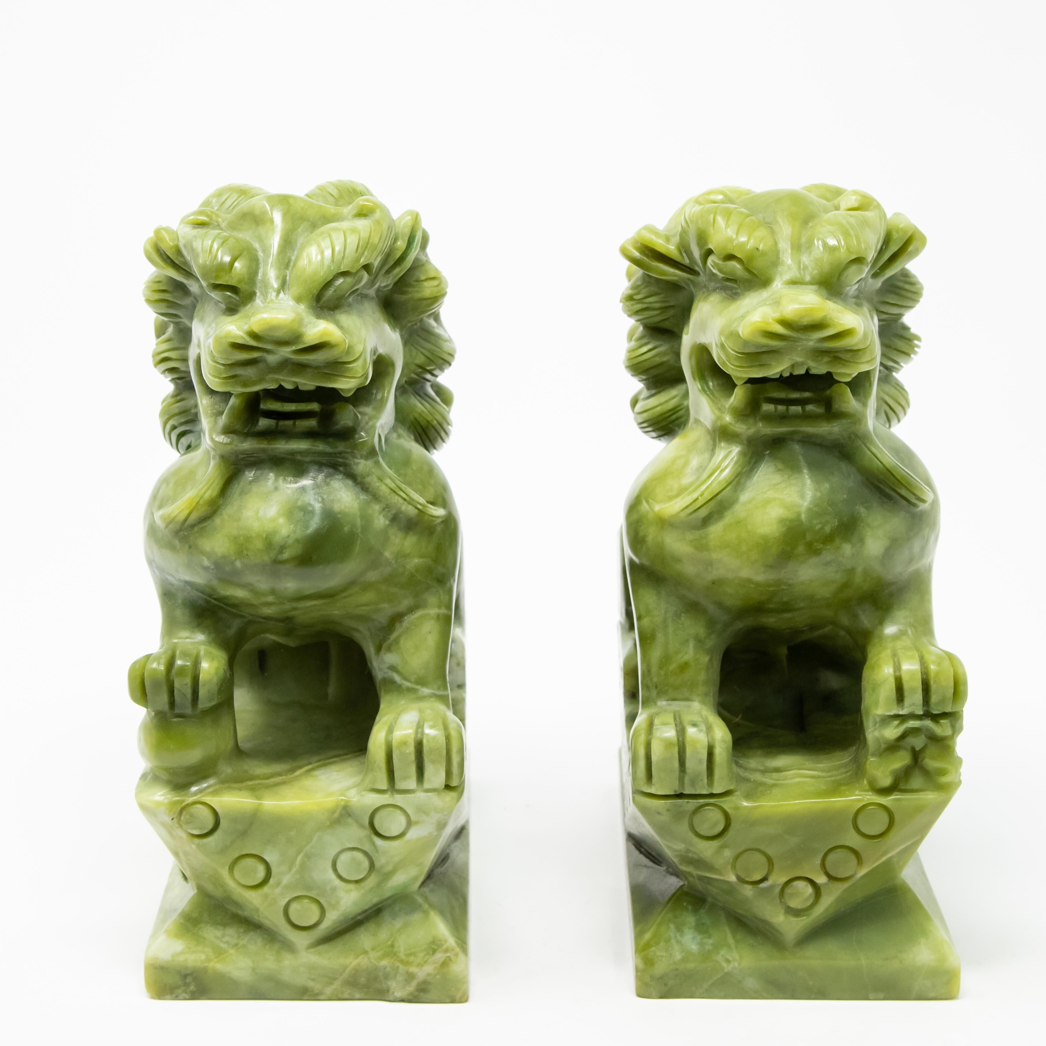 Offering this pair of stunning carved serpentine guardian lions. On rectangular plinths with geometric patterns and circles they rise up. One is guarding a ball under one foot and the other a baby lion. The carving of these are simple and the manes