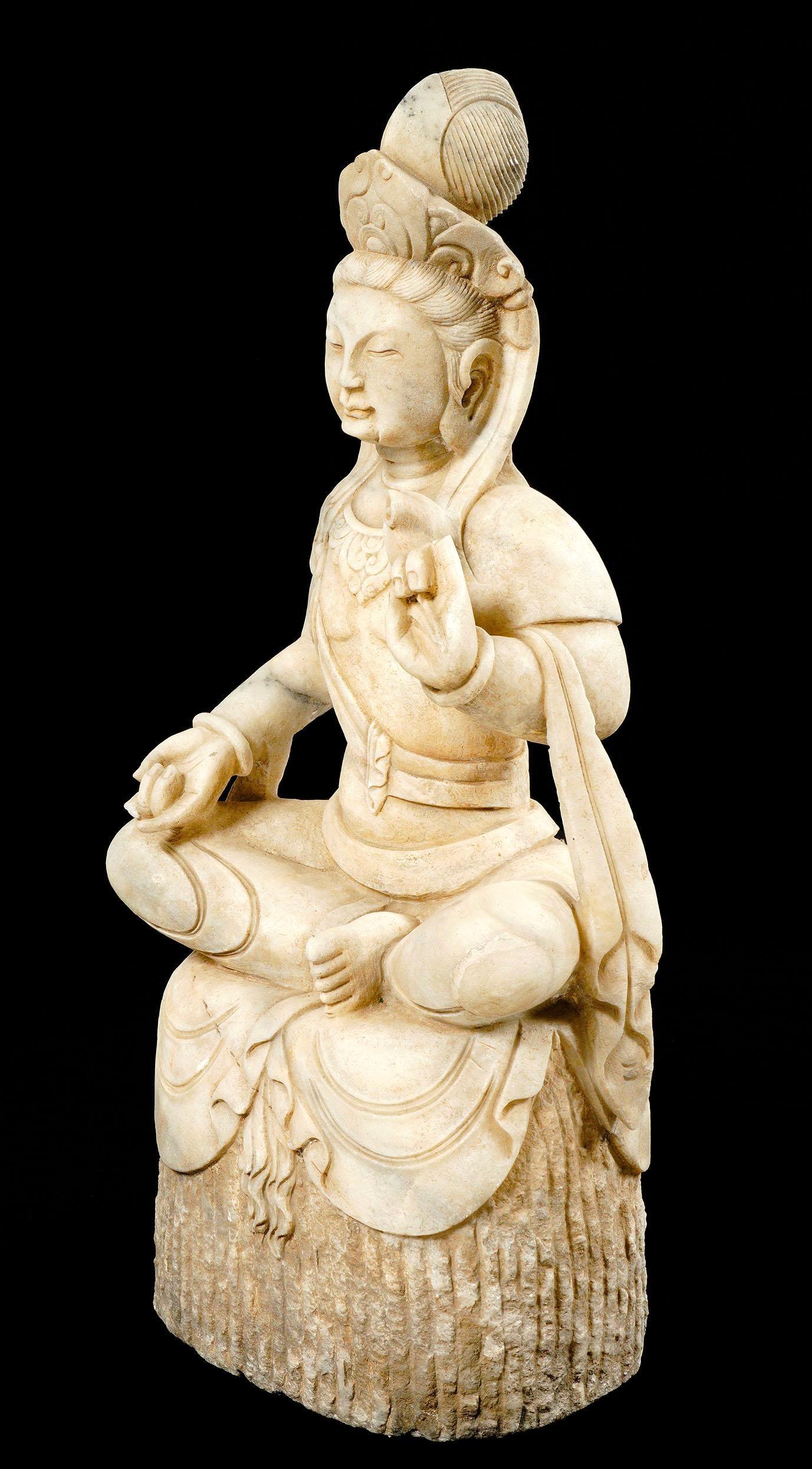 Statua in marmo della dea buddista Guanyin, seduta nella posizione del loto.  L'espressione tranquilla e serena del suo viso trasmette calma. È anche conosciuta come la 