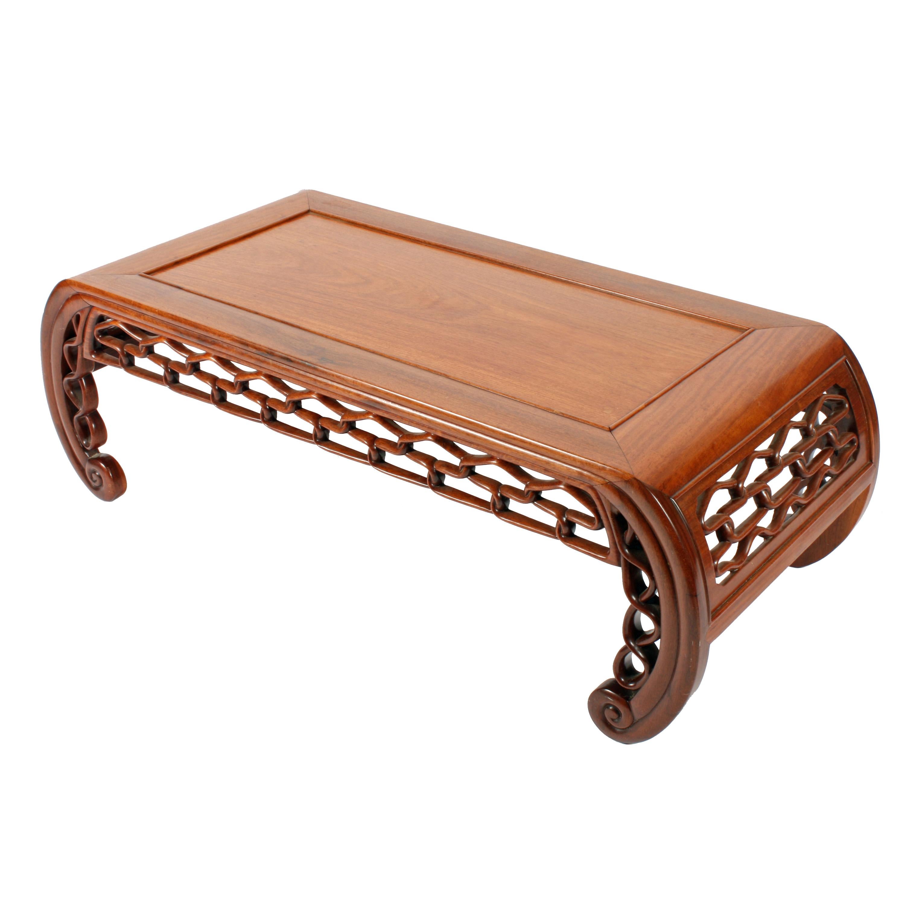 An early 20th century Chinese carved walnut opium or coffee table.

The table has a recessed single panel top with a moulded edge and the frame curves under at each end into legs with a scroll toe.

The frieze in-between the legs and at the
