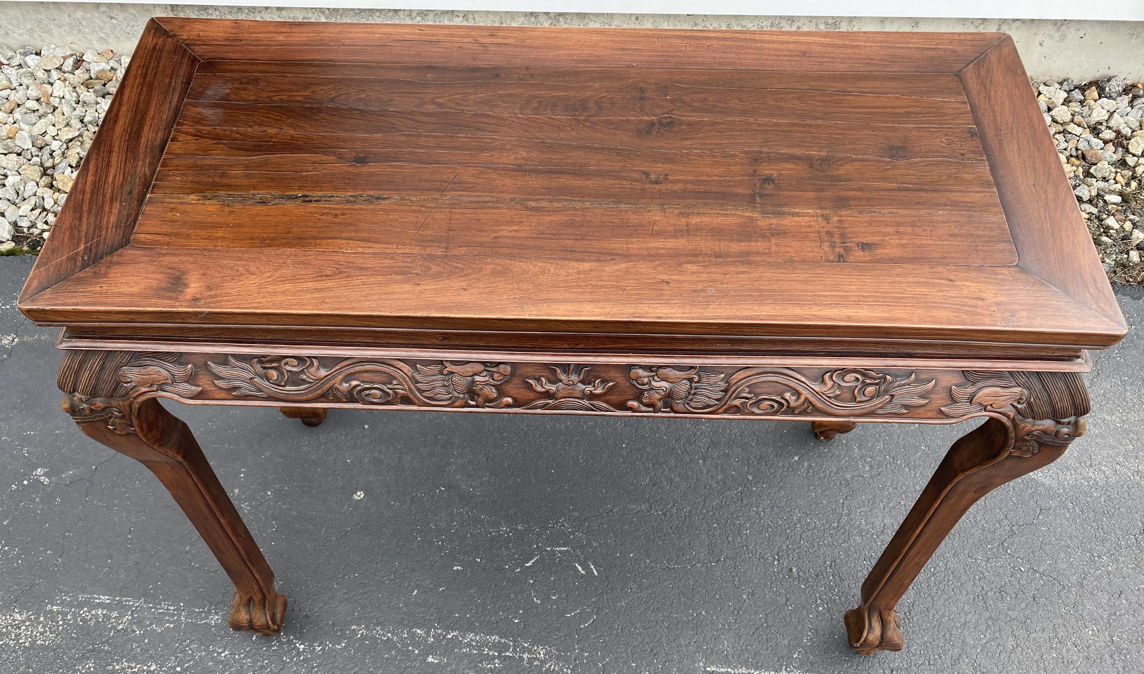 A fine and beautifully carved Chinese rosewood console or center table with carved dragon frieze decoration, and carved corner faces on each cabriole leg, terminating with paw feet. The table probably dates to the early 20th century is in very good
