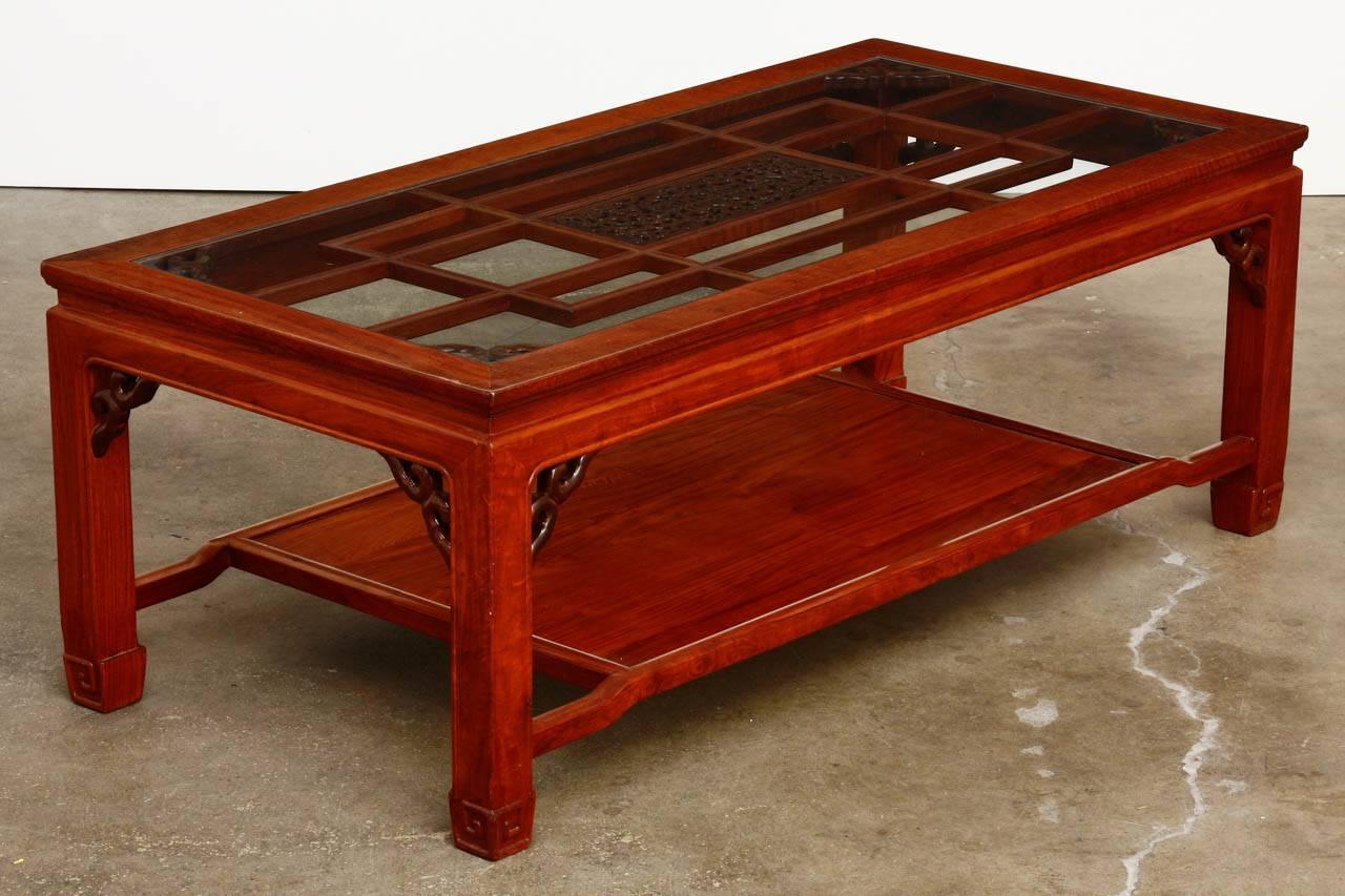 Exceptional Chinese carved two-tier coffee or cocktail table made of Huali rosewood. Features a radiant grain rosewood constructed in a two-tier design with a lower shelf. The top floating panel is inset with a geometric pattern centered by a darker