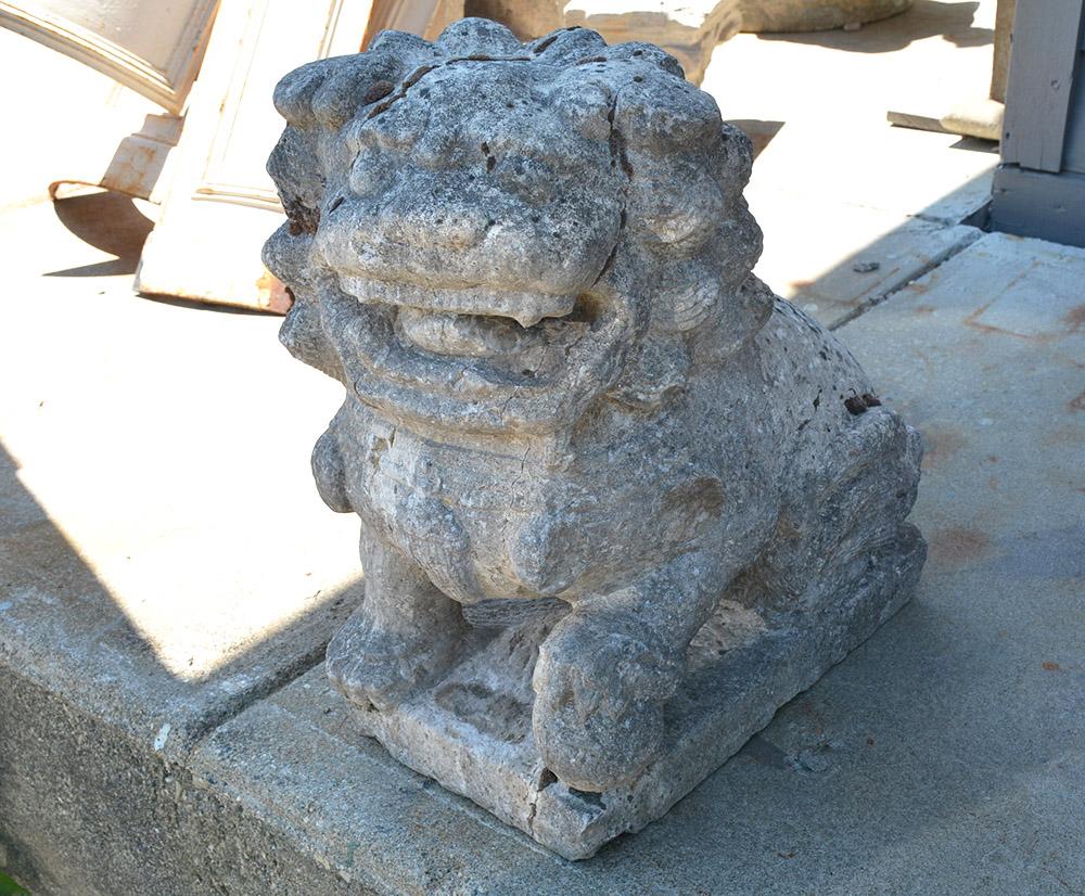 The features of this stone Foo lion has been softened by being exposed to the elements for many centuries. Still a very handsome sculptural specimen made from carved stone, it is known as Foo Dogs or Fu Dogs in western culture. The lion serves as