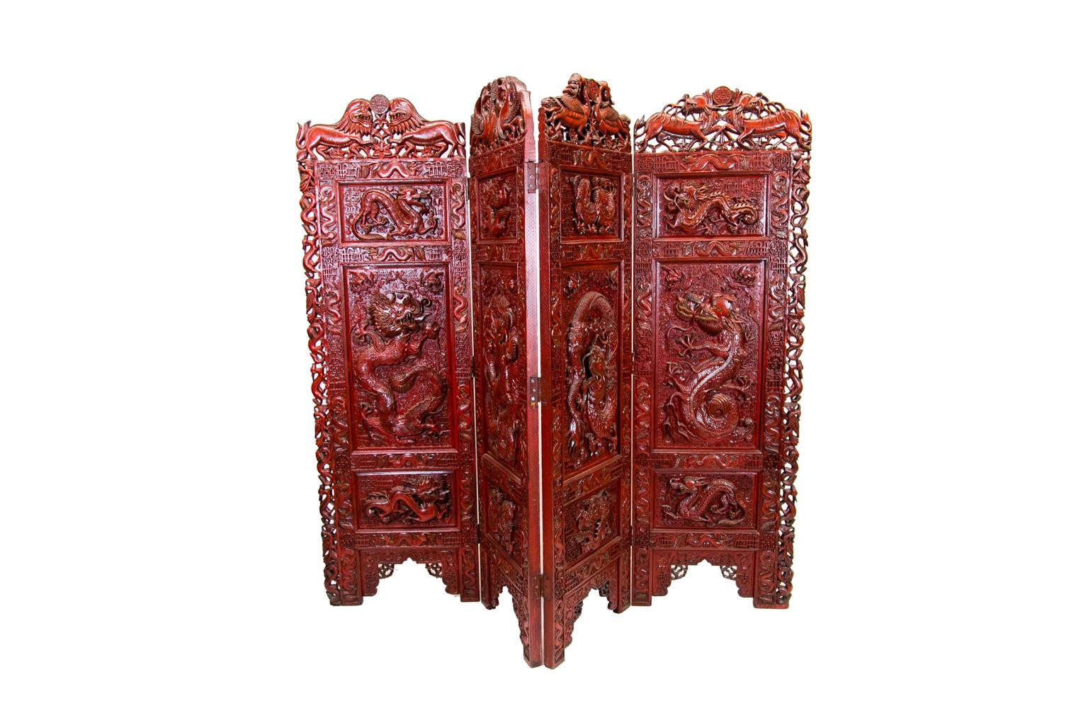 Chinese carved teak wood red lacquered four panel screen has elaborate intricate carving on both front and back sides. The front motif is of carved dragons with various Chinese characters. The back side is carved with urns, cattails, and flowers.
 