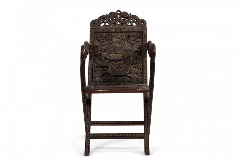 Asian Chinese style carved walnut folding campaign style arm chair with dragon carved back and arms (19th century).