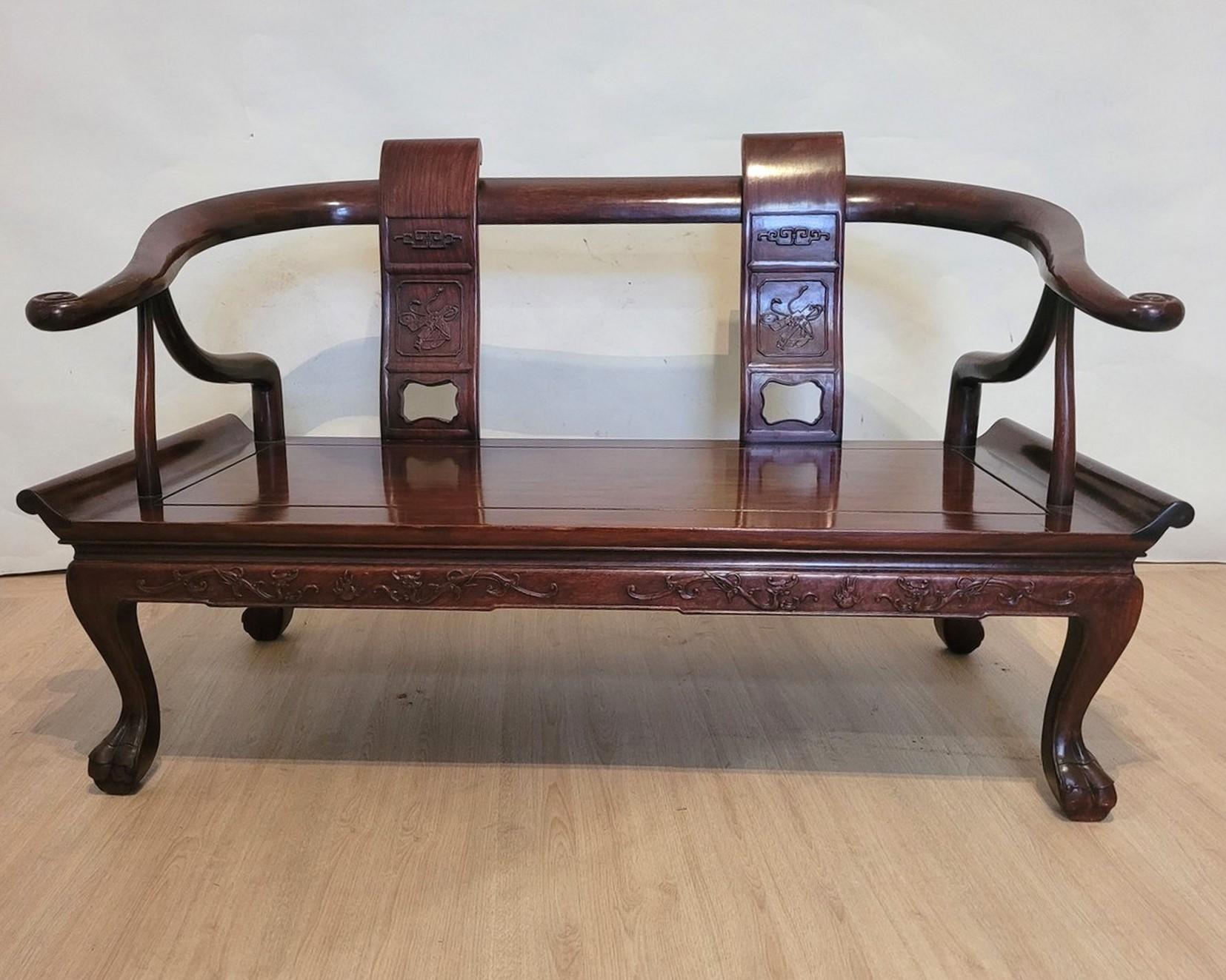 Very beautiful Chinese bench in carved exotic wood: the backrest comes forward to form the armrests and ends in snails, the backrest is also composed of 2 vertical wooden panels carved with symbols.
The feet are paw-shaped, the wooden seat is