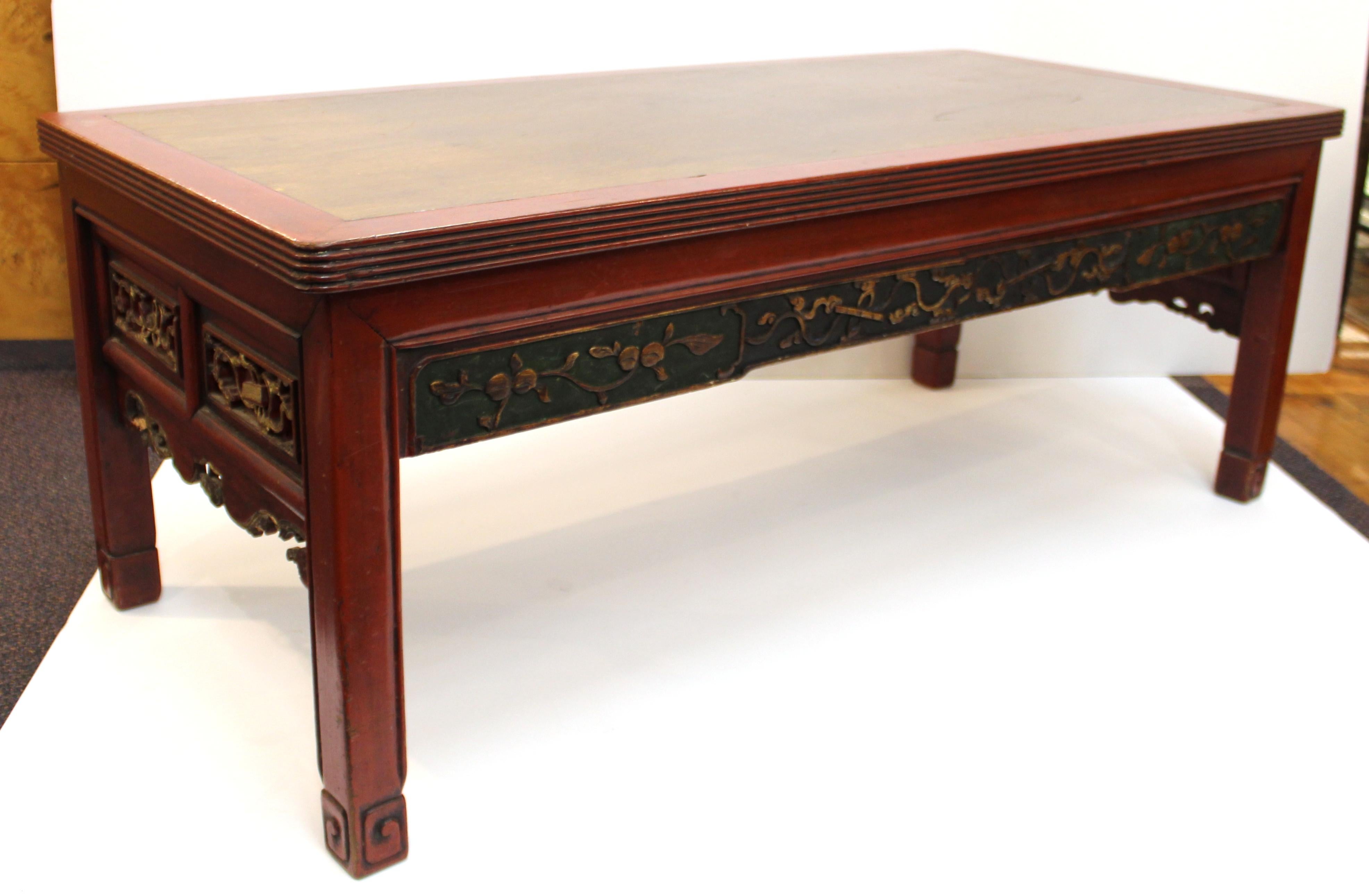 Chinese early 20th century cocktail or coffee table in carved wood, painted in red and gold accents. The piece was made during the 1920s and has a 'China' mark on one of the inside surfaces. In great vintage condition with some age-appropriate wear.