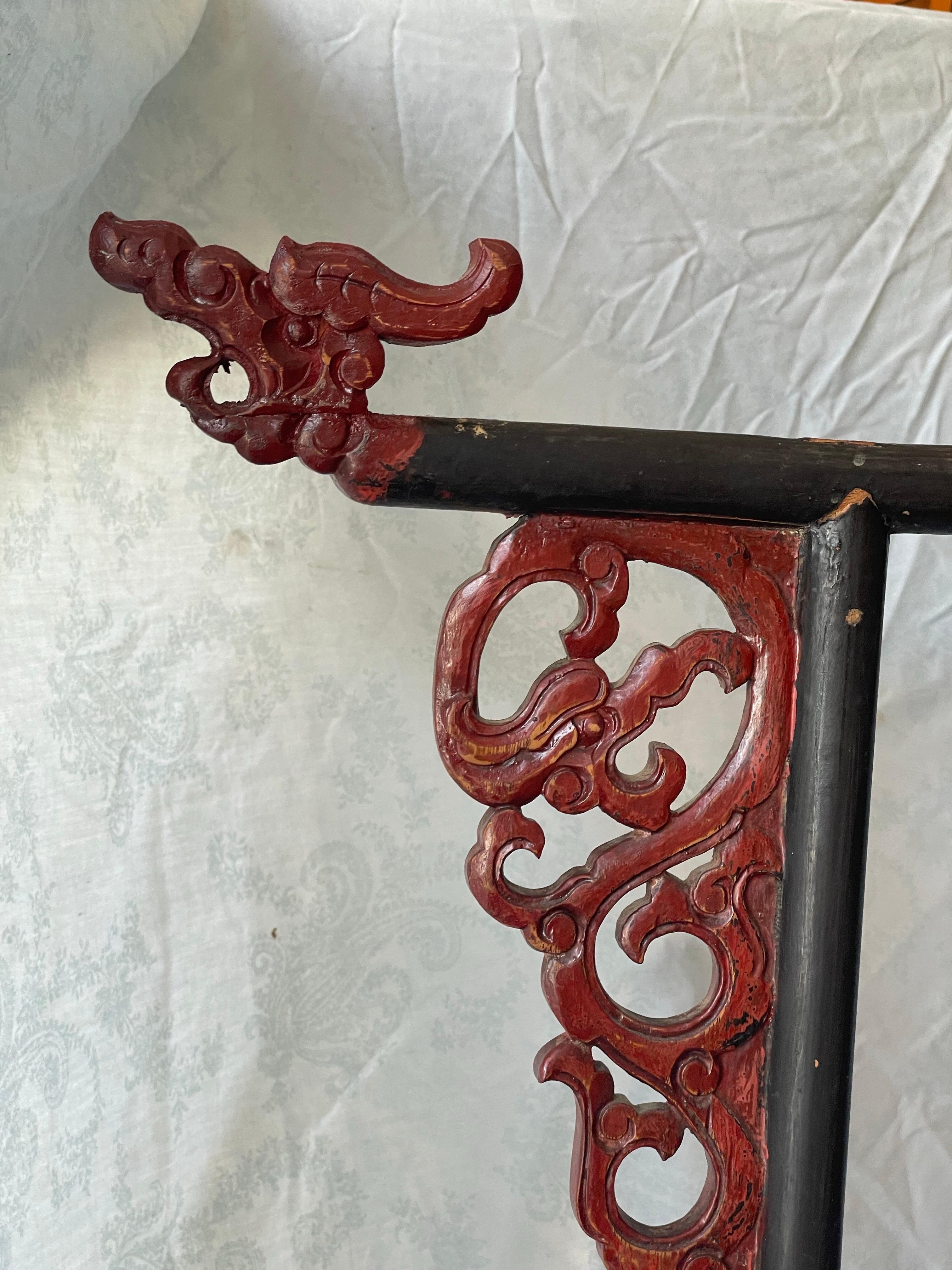 Here is a great looking wooden Chinese robe display rack painted classic smooth black with cinnabar red accents, including the wonderful carved dragon heads which are overlooking and protecting all. The piece is decorated with other traditional