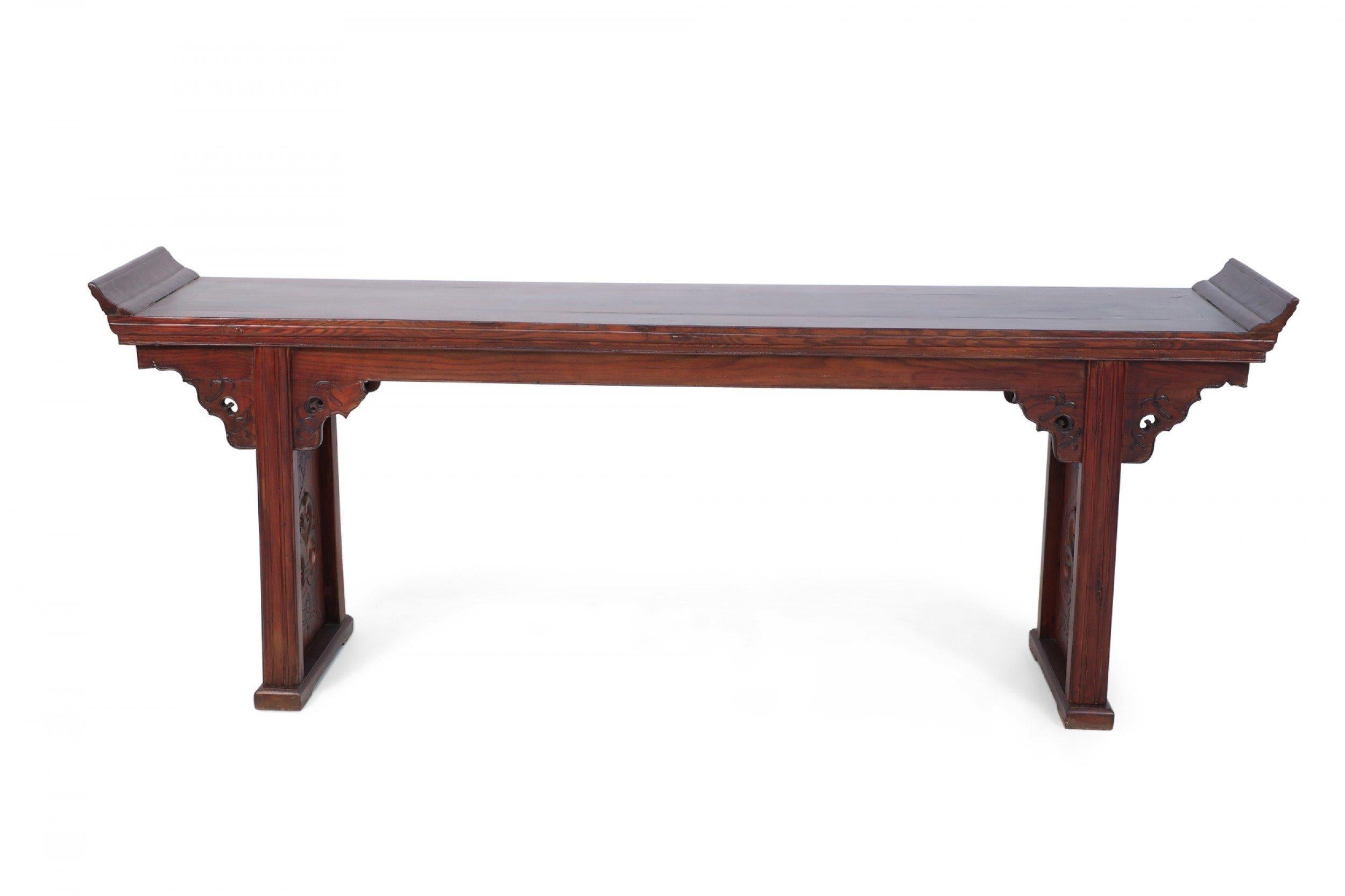 Chinese hardwood altar / console table accented with ornately carved and pierced spandrels and recessed legs and topped with a surface bearing gently sloping sides.