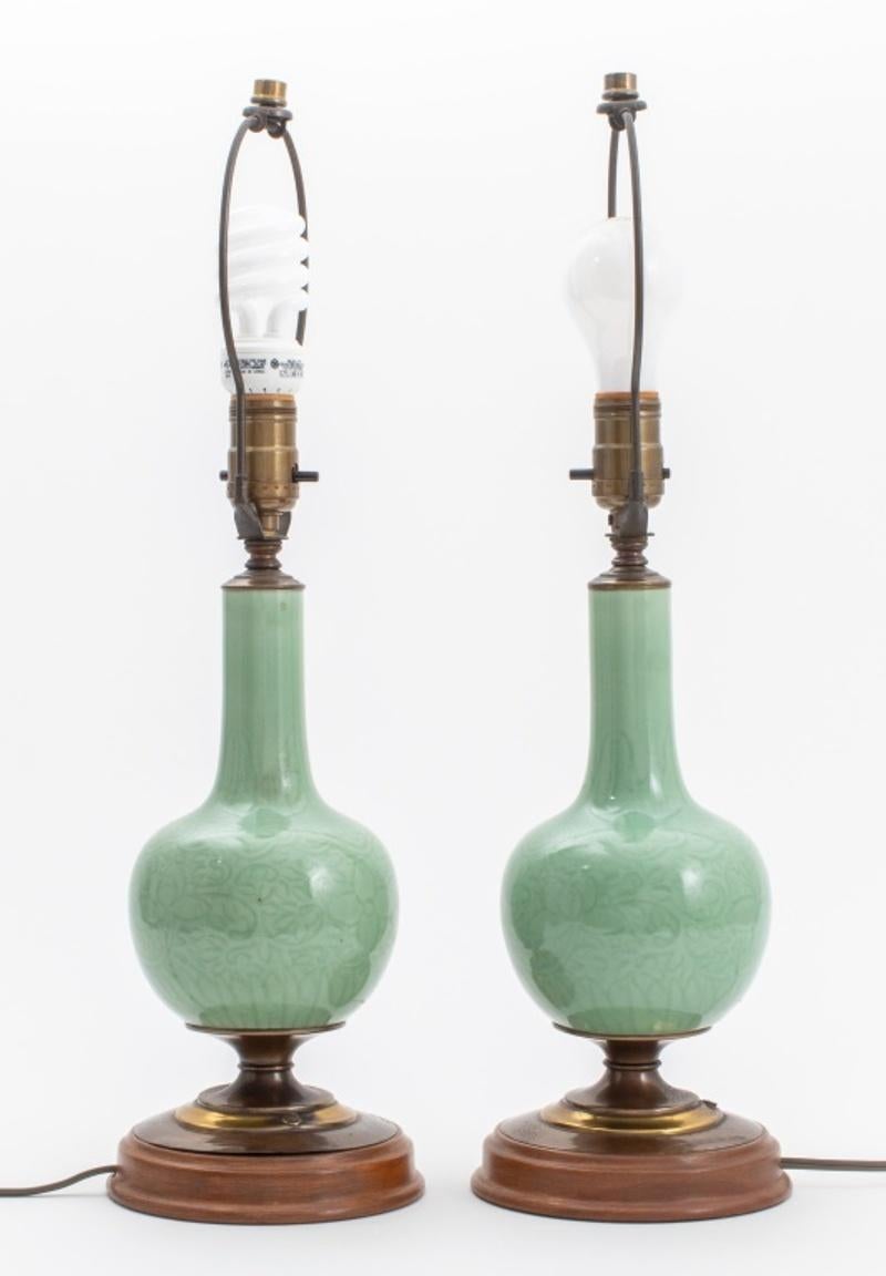 Pair of Chinese celadon glazed ceramic porcelain bottle vases mounted as lamps, the vessels with incised scrolling floral decoration and ruyi borders, mounted with gilt brass on hardwood bases. Each: 21.25