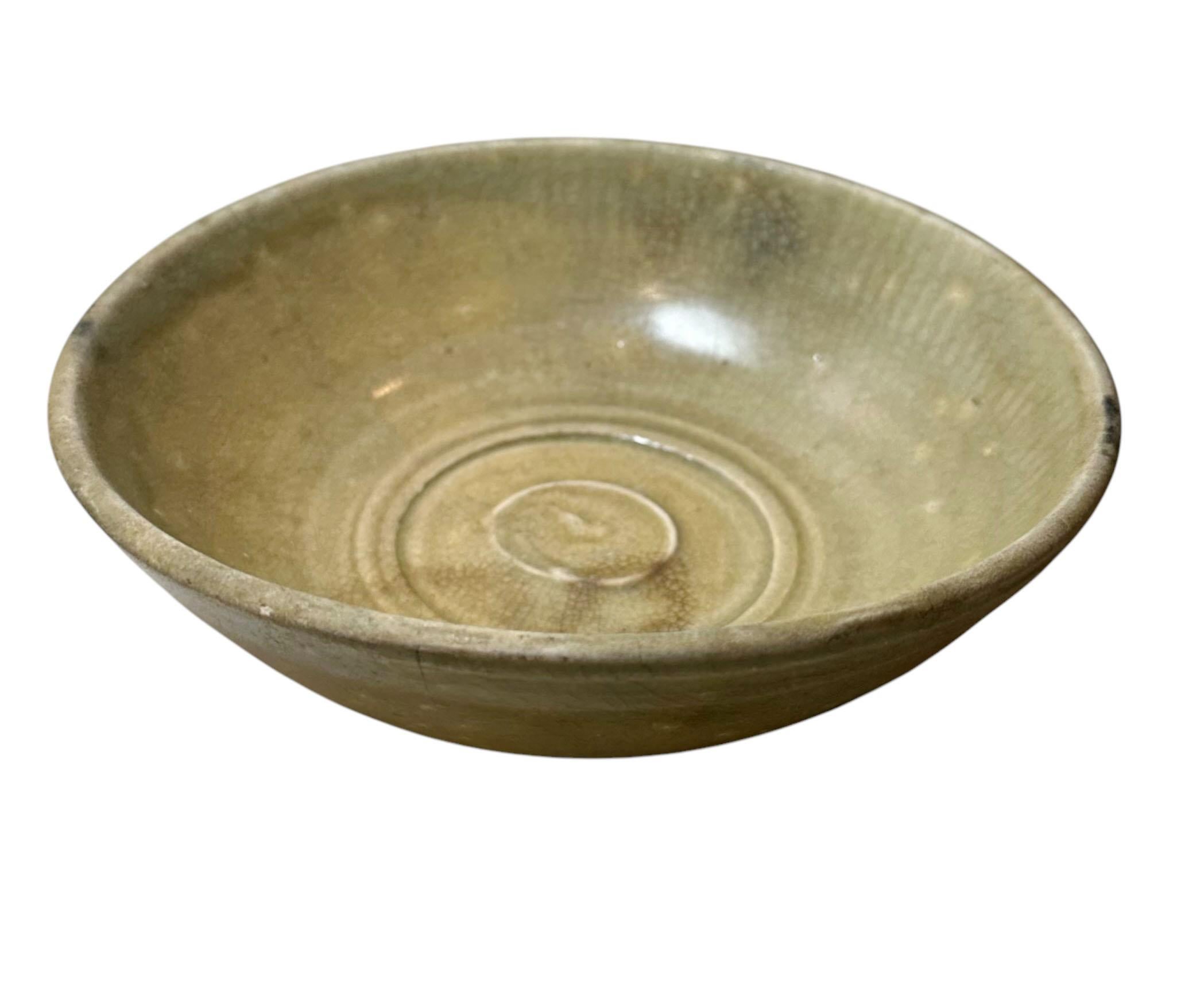 Una ciotola cinese in celadon della prima dinastia Ming con un disegno a volute al centro e in parte sui lati, con molte crepe. Cina, dinastia Ming, quindi potrebbero risalire a un periodo compreso tra il 1300 e il 1600.
