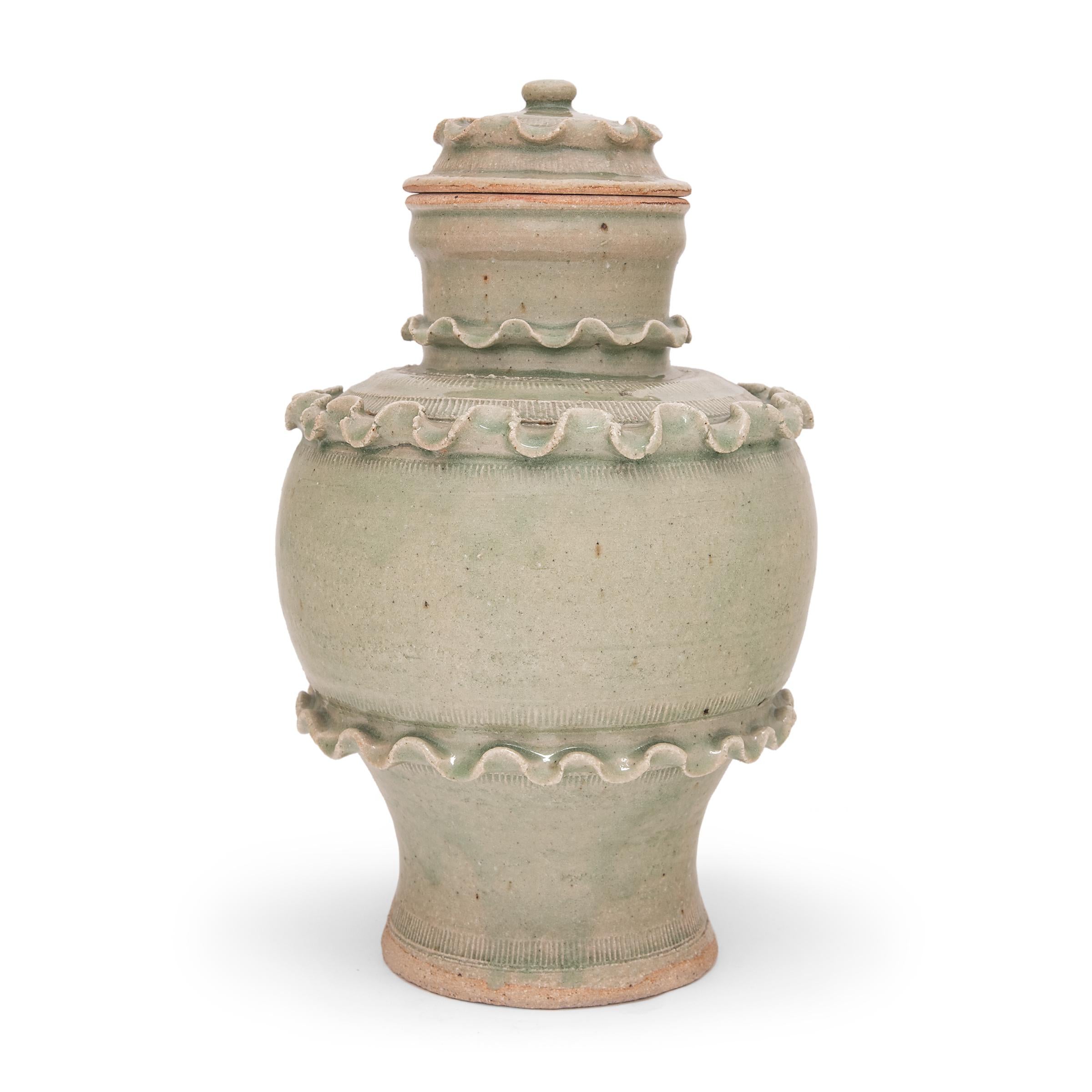 This green glazed jar is designed in the style of ancient Chinese ceremonial vessels found in temples or tombs. Often elaborately decorated with miniature figures and relief patterns, such vessels were used for storing food offerings to the gods or