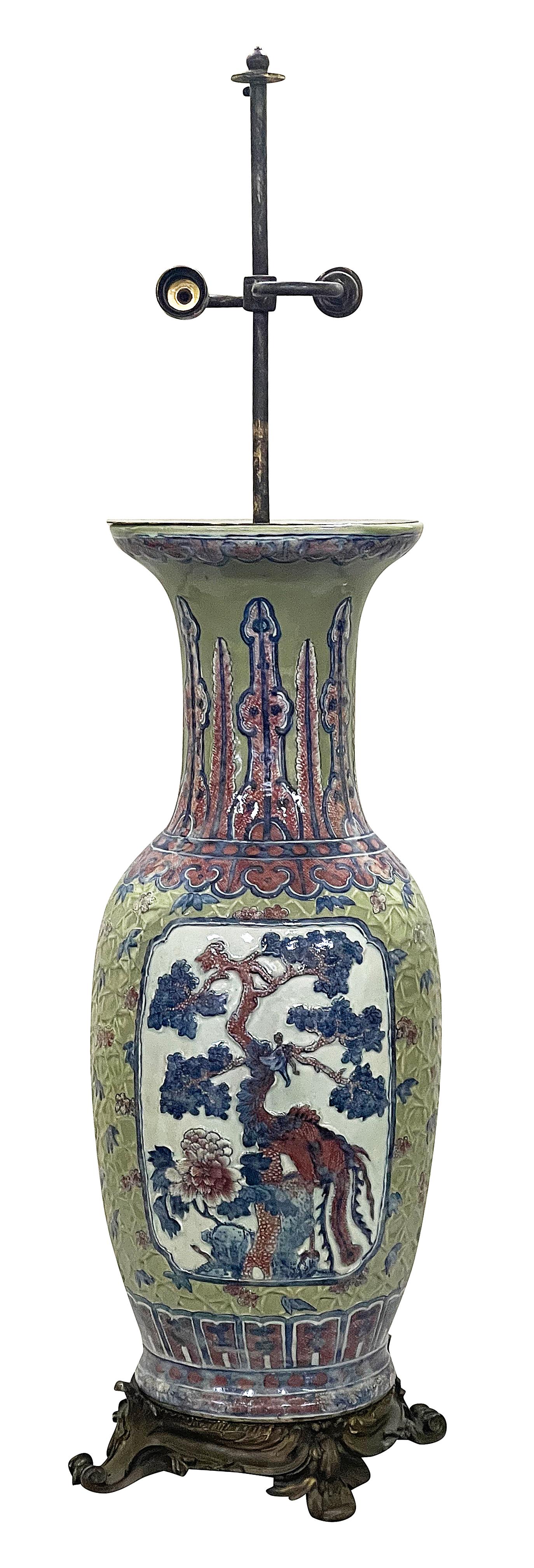 This exquisite Chinese Celadon vase from the early 19th century is remarkable for its unusual relief decoration, showcasing intricate motifs of flora and fauna. The vase is adorned with vivid colors, featuring a striking depiction of a tree and a