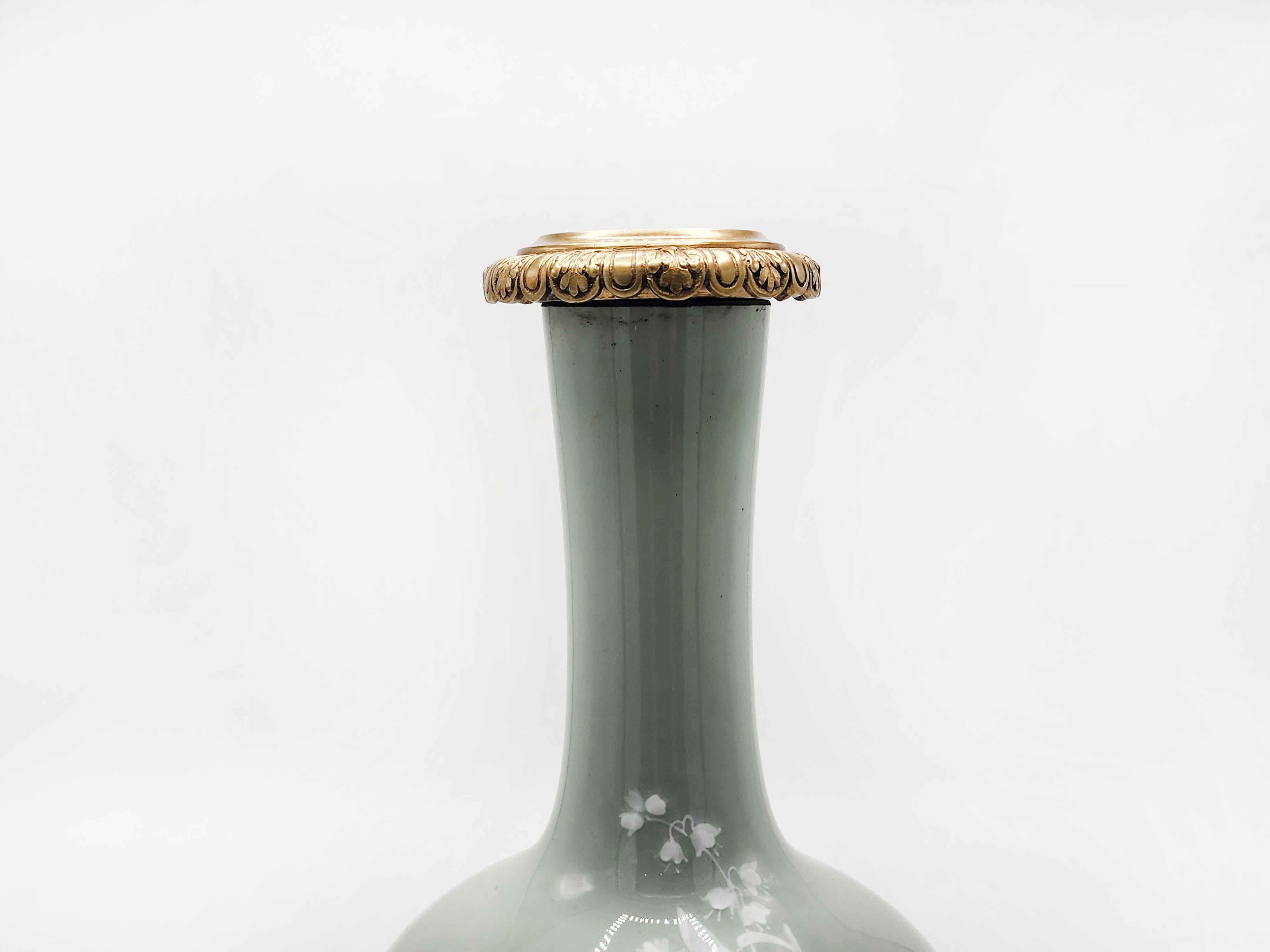 Vaso cinese di porcellana celadon con bronzo
Squisito vaso in porcellana con corpo bulboso e collo allungato, decorato con delicati fiori bianchi su sfondo verde celeste. La base e il collo sono montati in bronzo dorato, conferendo un'aria