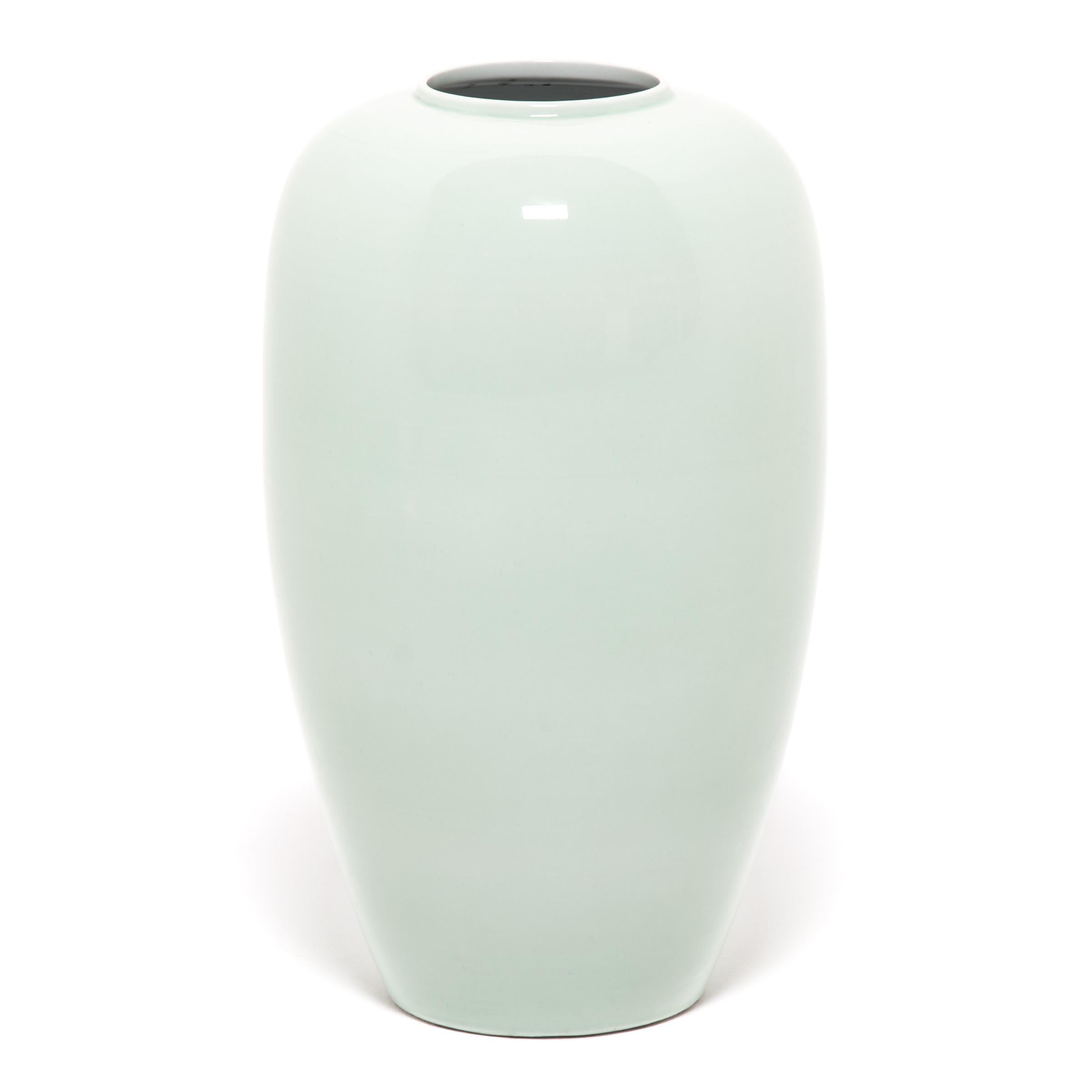 For centuries, collectors have coveted fine celadon ceramics like this elegant contemporary tapered vase. The glazing process is complex: an artisan covered the vase in liquid iron-rich clay, and then with a glaze that reacts to the iron to create