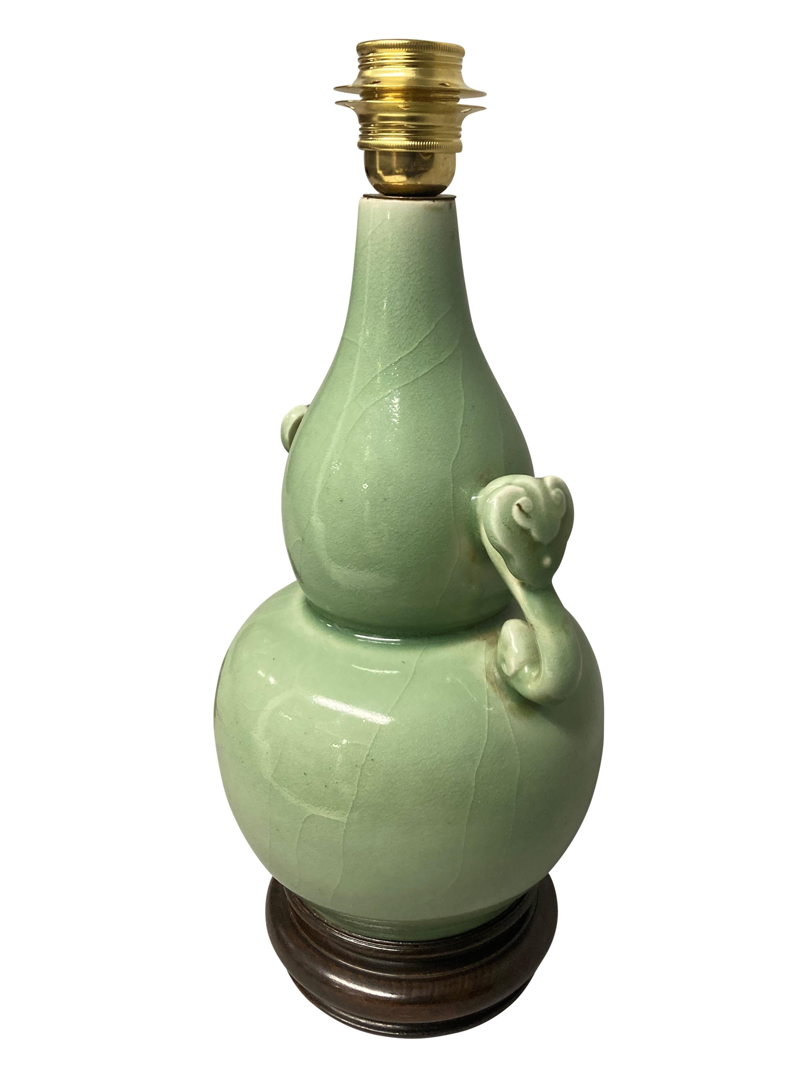 A Chinese celadon twin handled vase lamp, on a carved hardwood base.