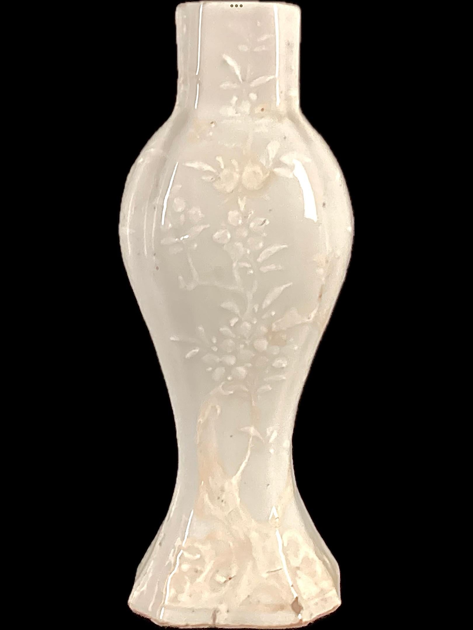 Vaso cinese in porcellana celadon. Il vaso presenta uno smalto ceramico di colore verde chiaro con un motivo floreale e faunistico bianco in rilievo. Il vaso ha un collo leggermente allungato con un'ampia parte centrale e una base svasata. I fiori