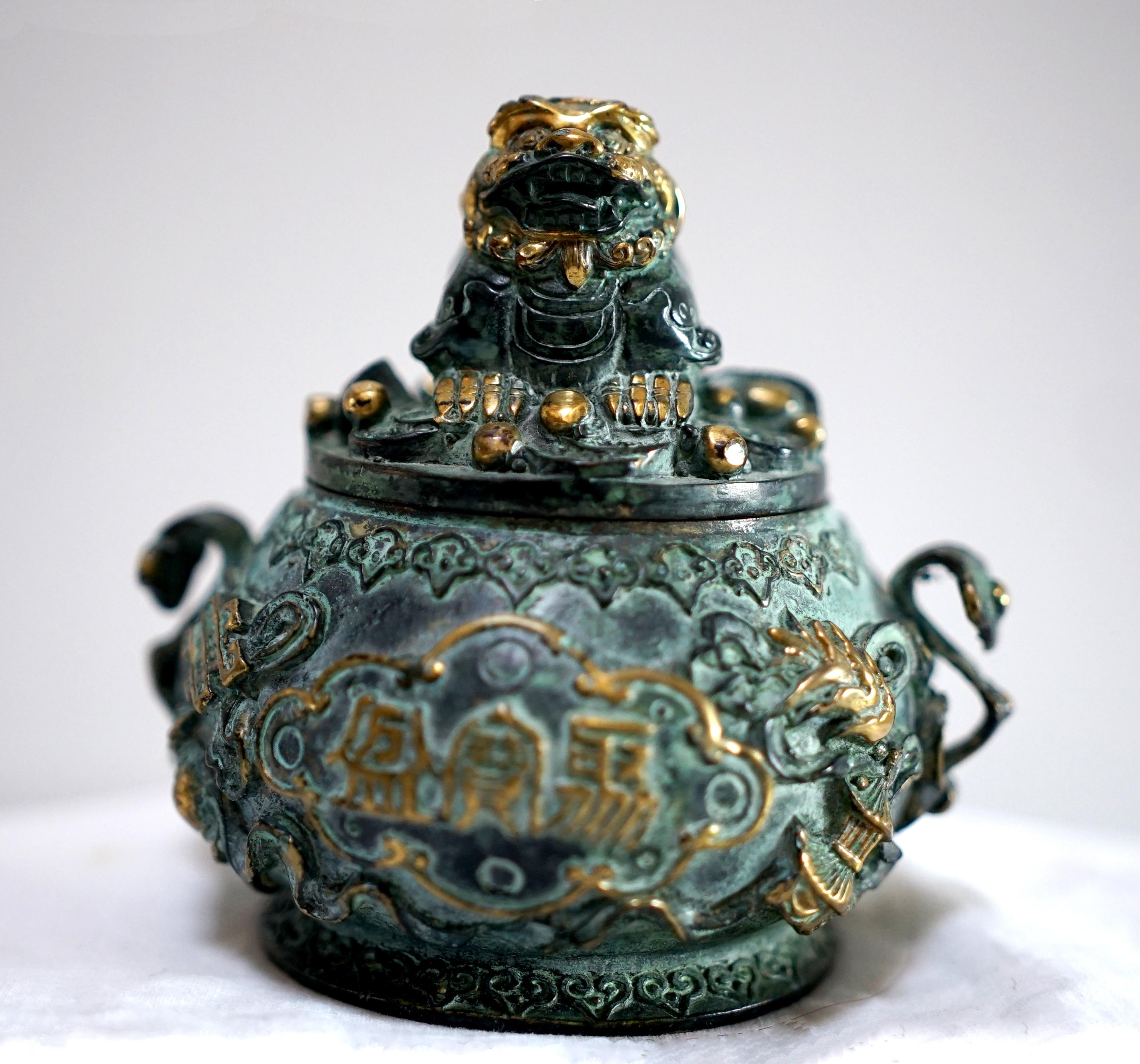Bronze and gilt detailing combine to make this Chinese censer a beautiful decorative cast bronze accent. The bowl and cover are cast with various objects, small and bright like a fish, with other lucky auspicious objects and characters that connote